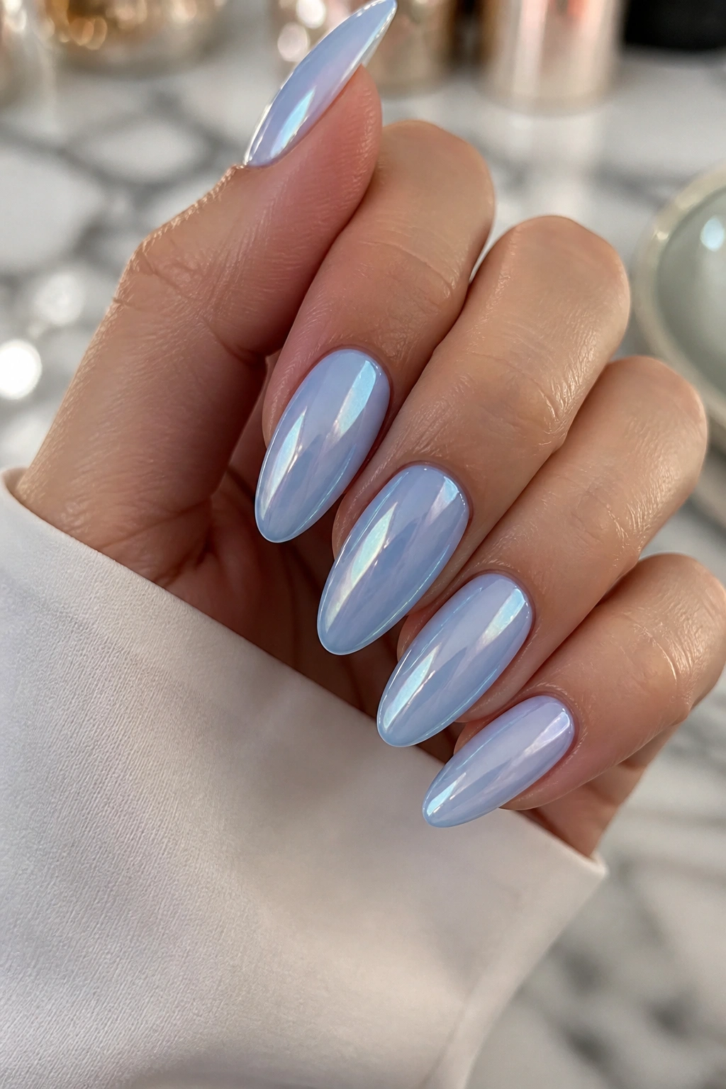 Close-up of almond nails with glazed light blue polish on a real hand