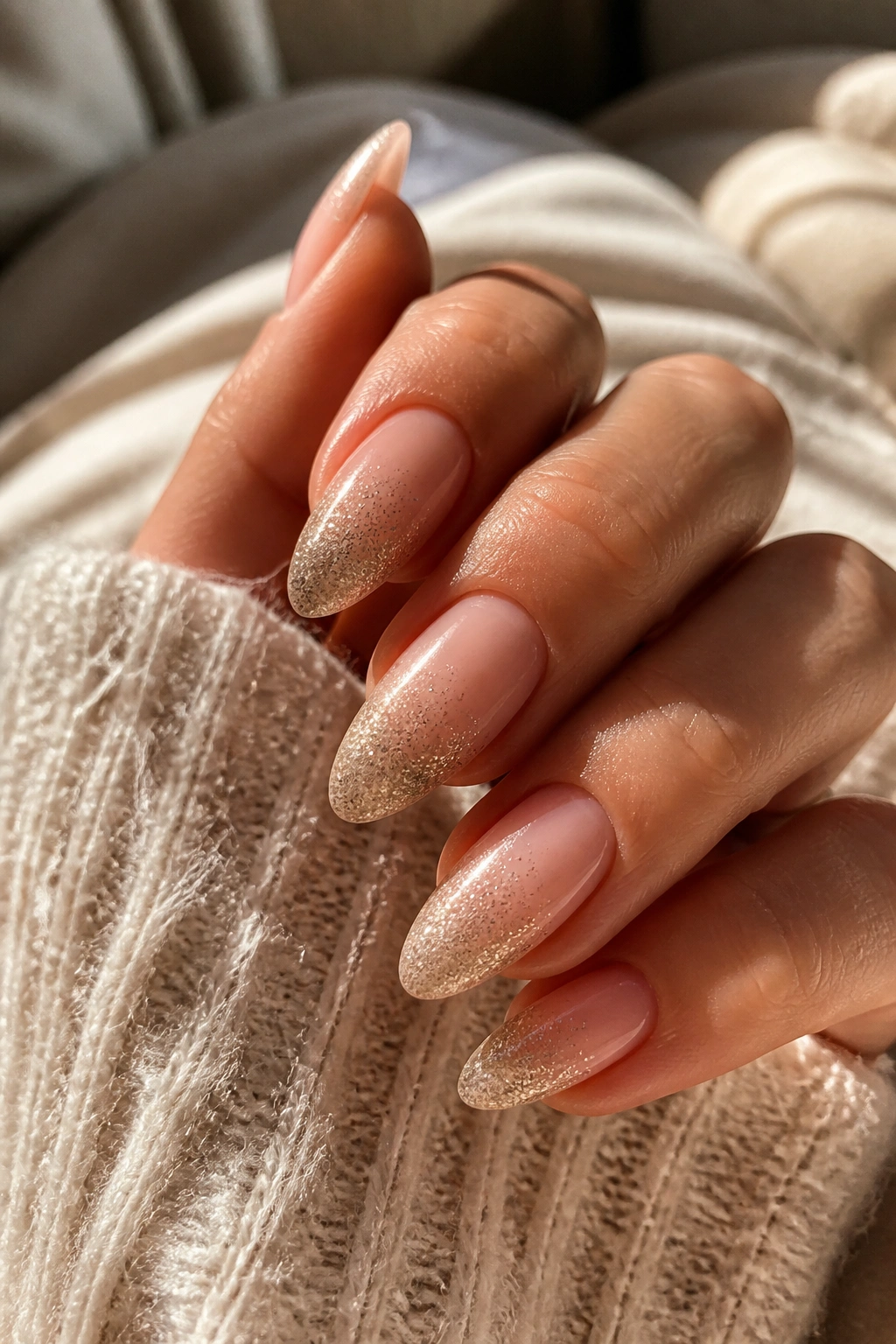 Close-up of sheer nude glitter fade ombre almond nails on a real hand