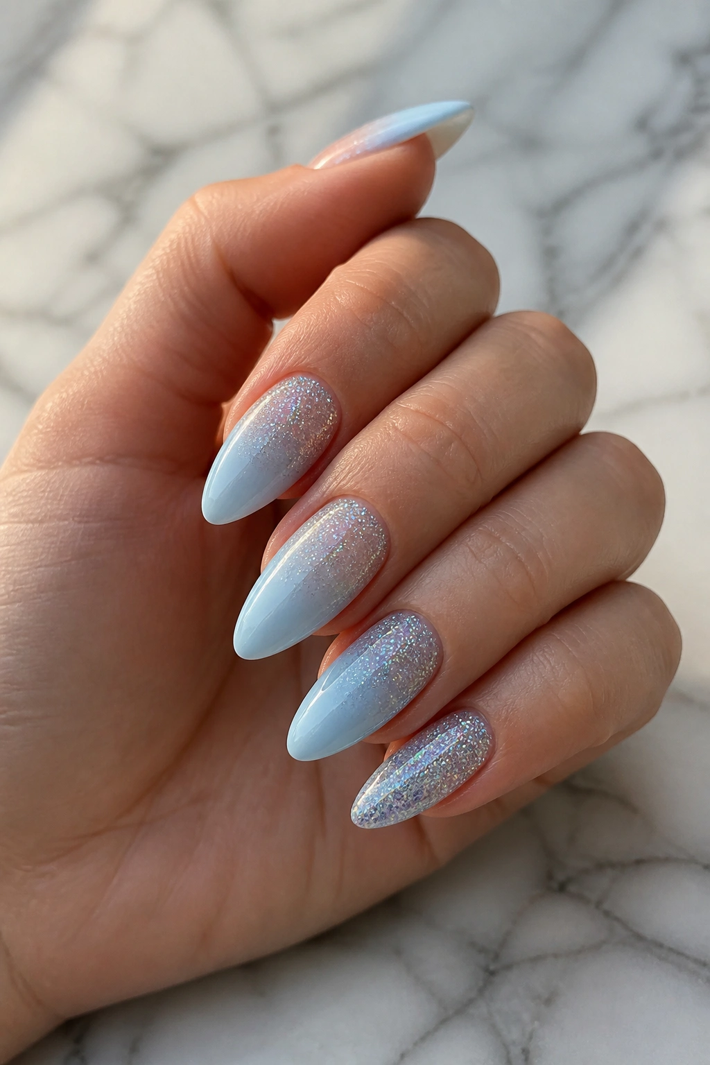 Almond nails with glitter ombre on pastel blue base on real hand