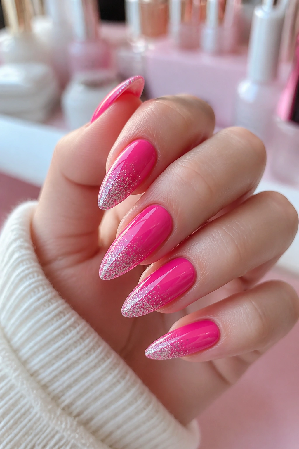 Close-up of glitter-tipped hot pink almond nails on a real hand