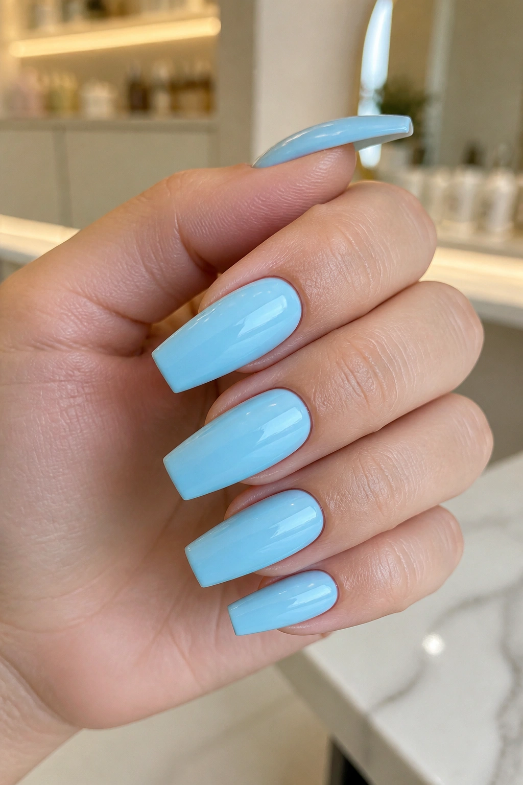 Close-up of glossy baby blue coffin nails with square tips on a real hand