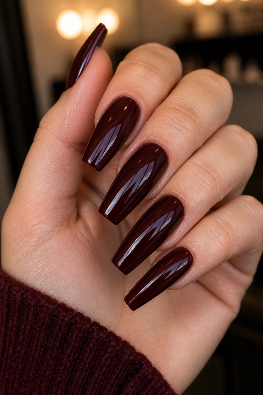Close-up of glossy deep wine burgundy coffin nails with high-shine finish.