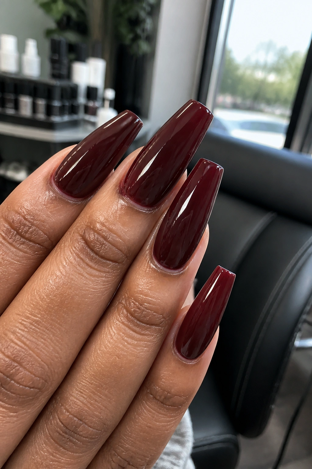 Hand with glossy deep wine burgundy coffin nails and clean sidewalls