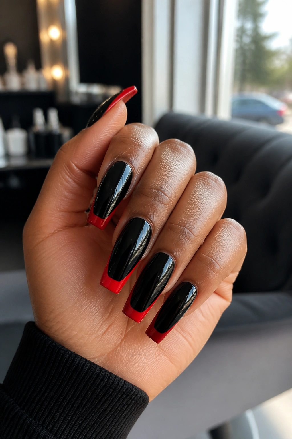 Close-up of glossy red and black coffin nails on a real hand