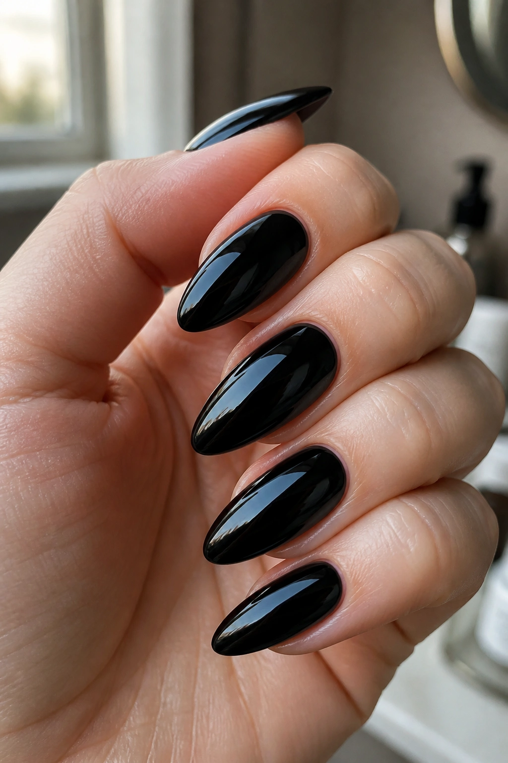 Close-up of glossy jet-black almond nails on a real hand