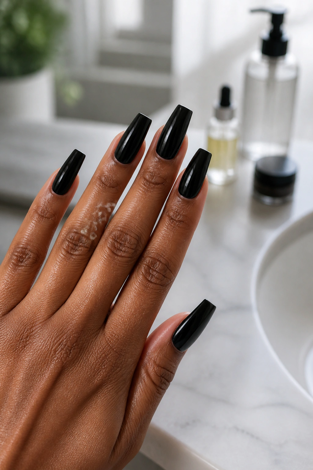 Close-up of hands with glossy black coffin nails in a clean vanity setting