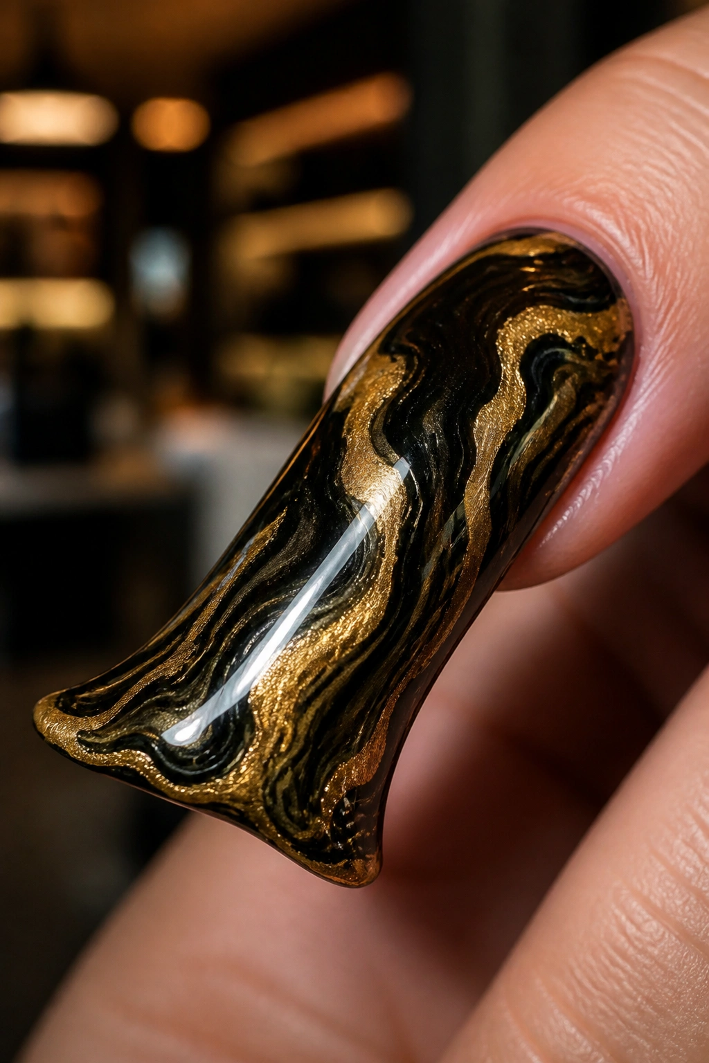 Close-up of gold and black marble duck nail on a real hand in a warm salon