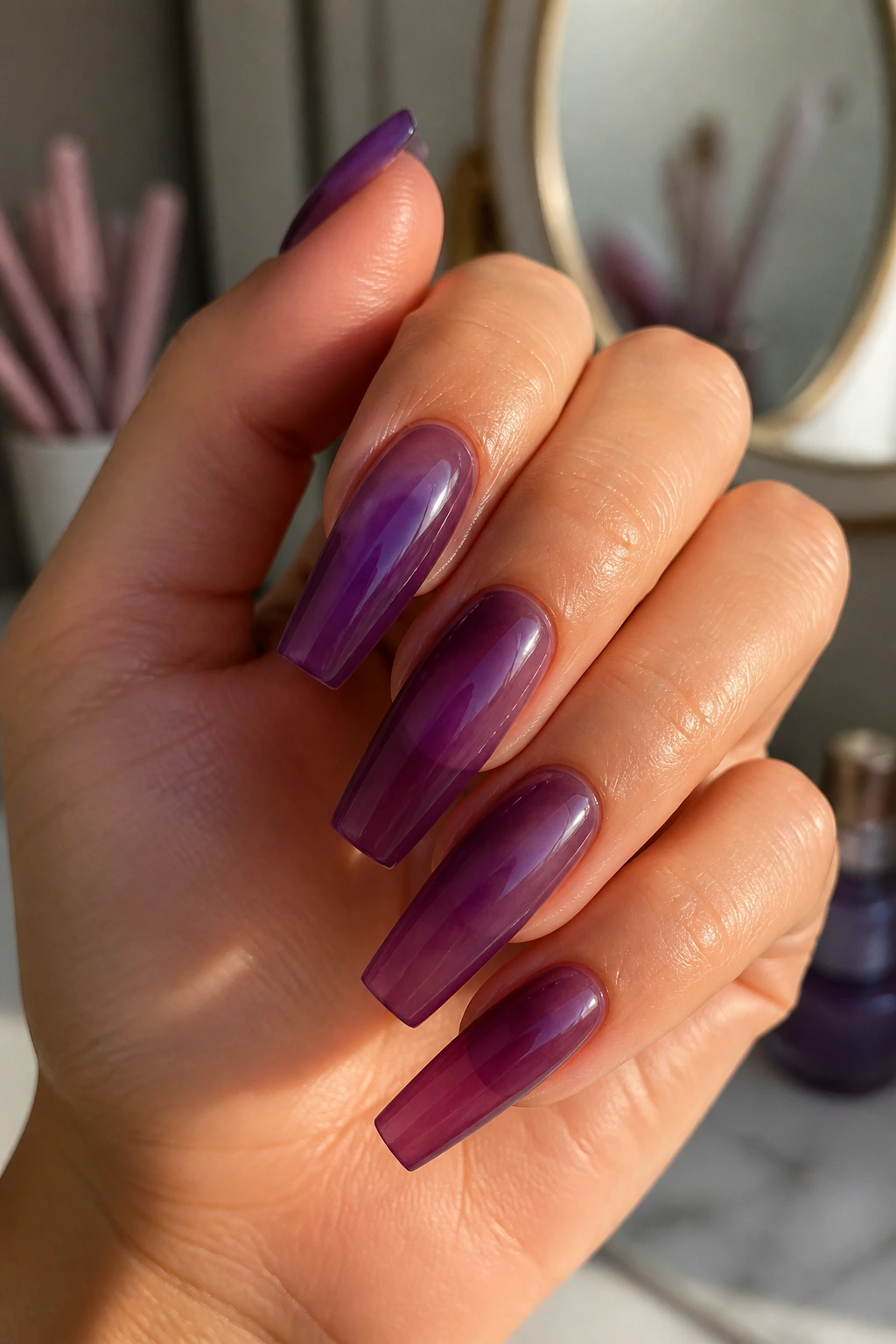Close-up of grape jelly coffin nails with sheer finish on a real hand