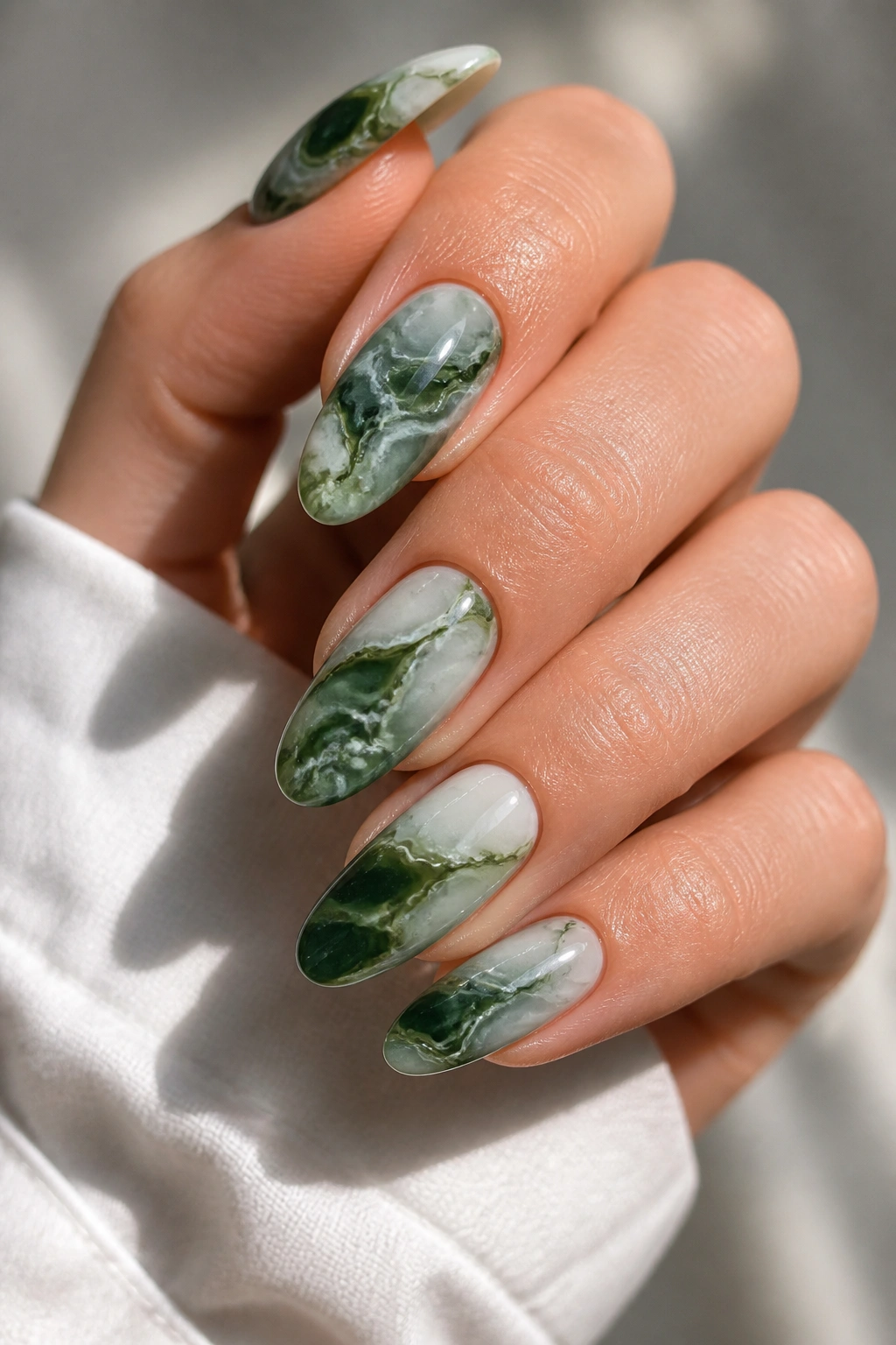 Close-up of real hand with green marble almond nails showing marbled veining