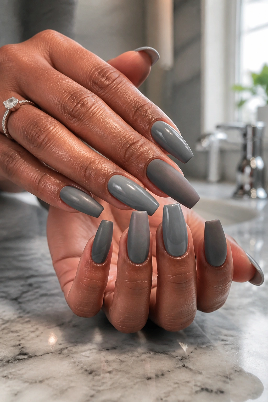 Close-up of grey coffin nails on real person's hands in bathroom setting