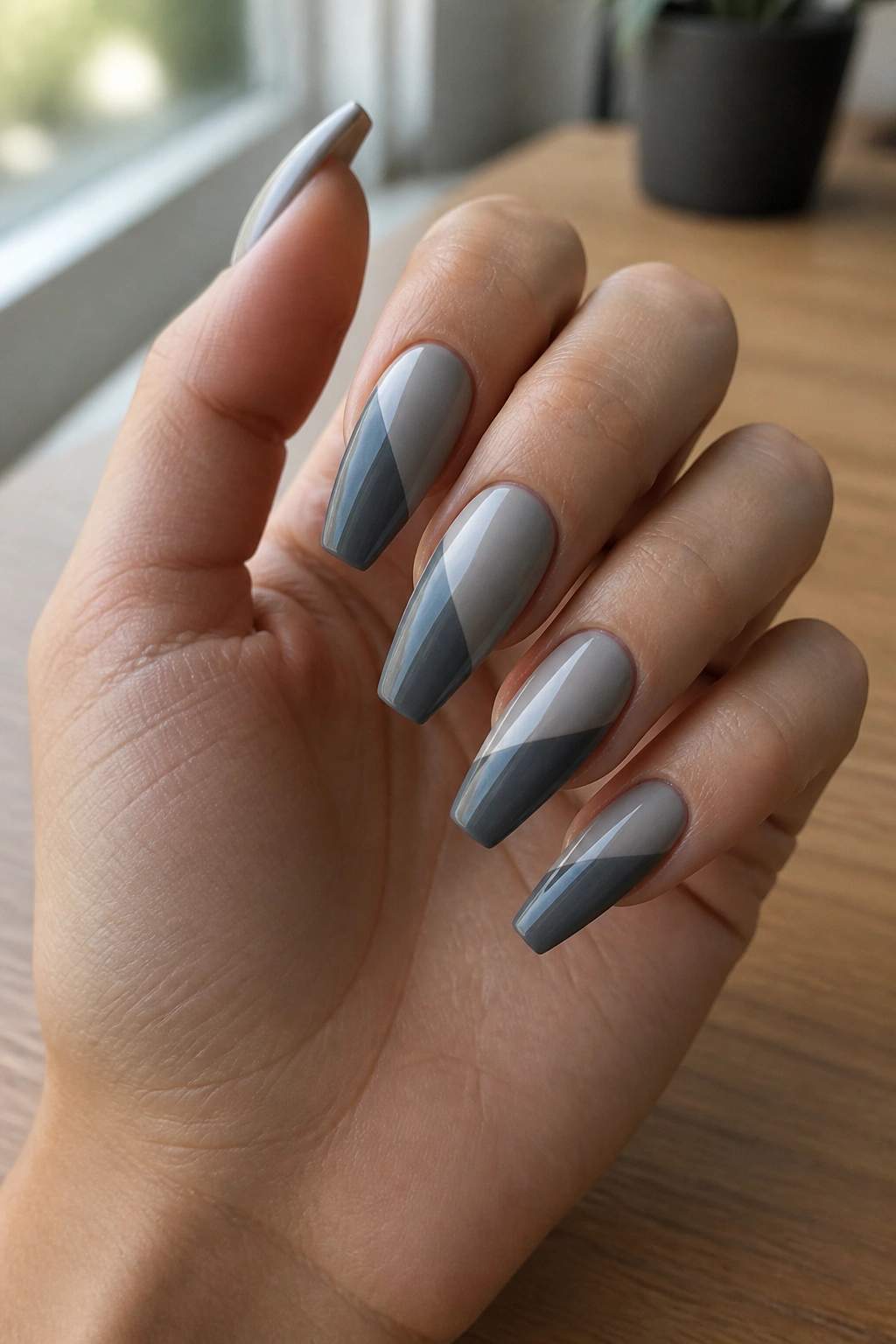 Close-up of two-tone grey diagonal-panel nails on a real hand.