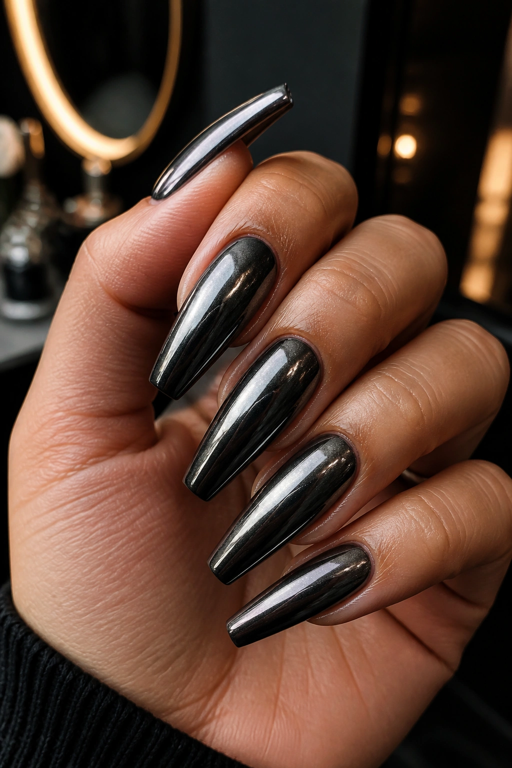 Close-up of gunmetal chrome coffin nails on a hand.