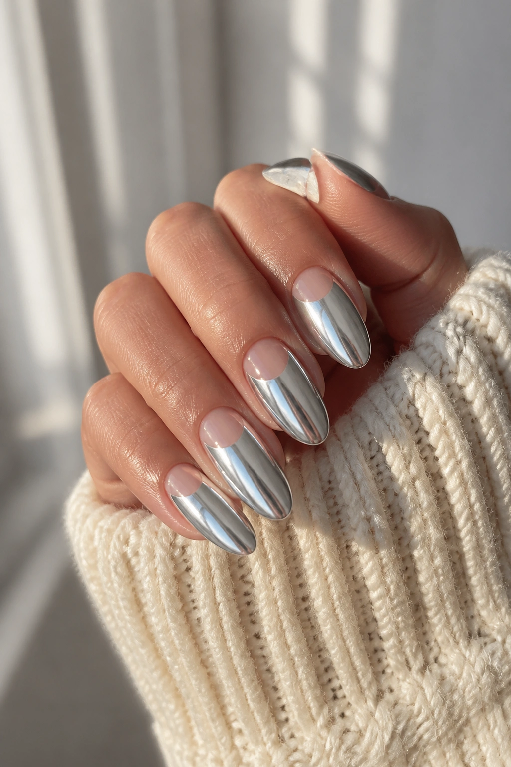 Almond nails with nude half-moon and chrome top on a hand