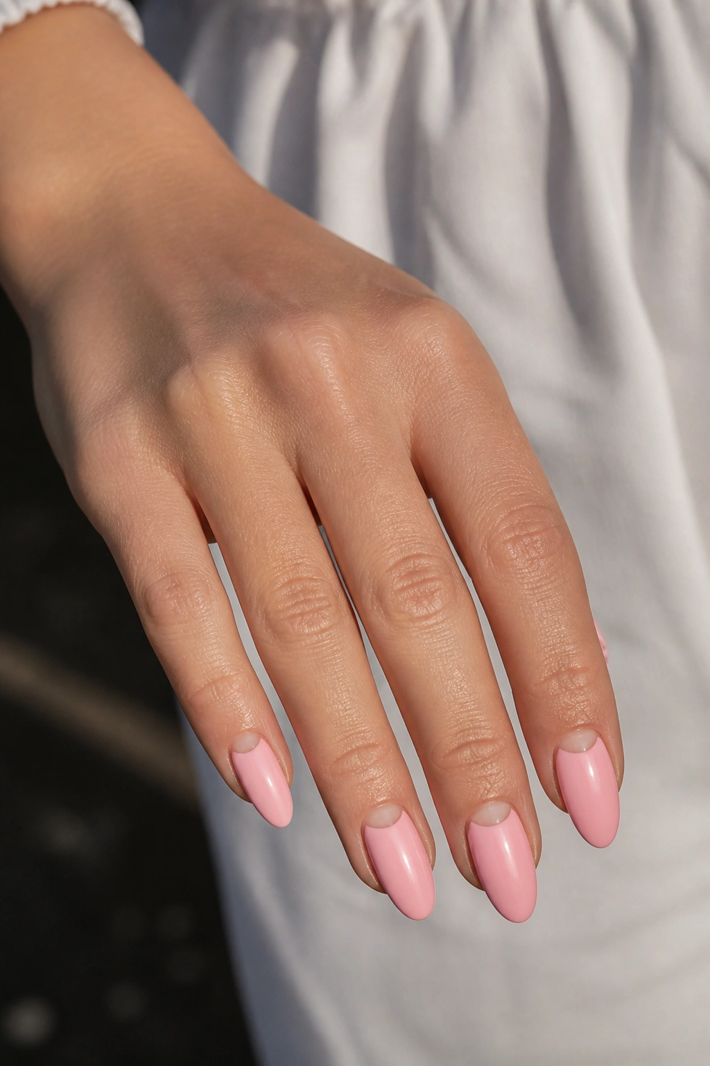Close-up half-moon pink almond nails with negative space