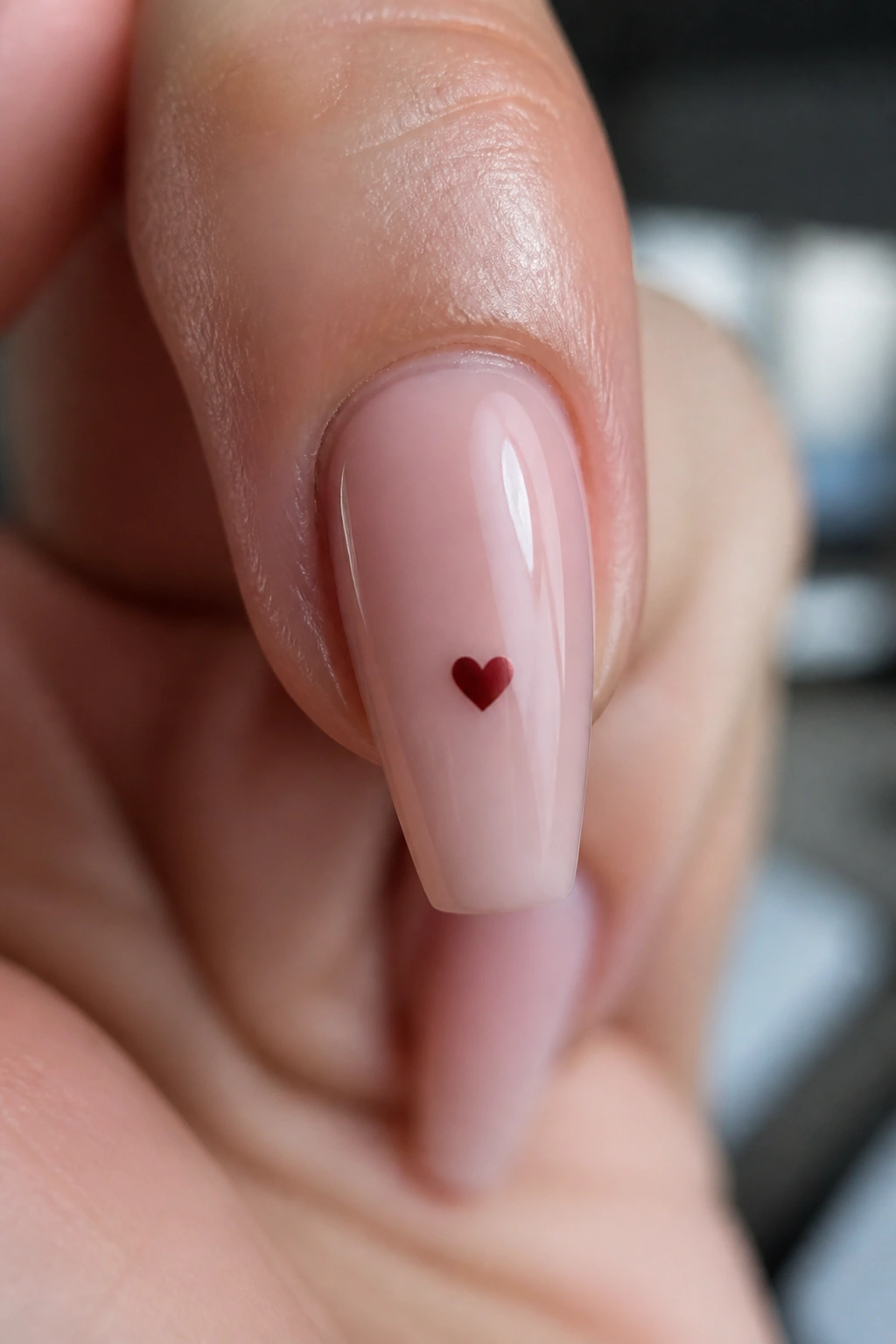 Close-up of a coffin nail with a small heart on a real hand in a salon setting.