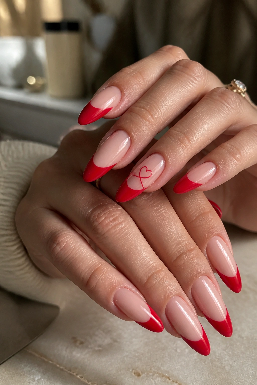 Close-up of a real hand with long almond nails showing a tiny red heartline on one nail