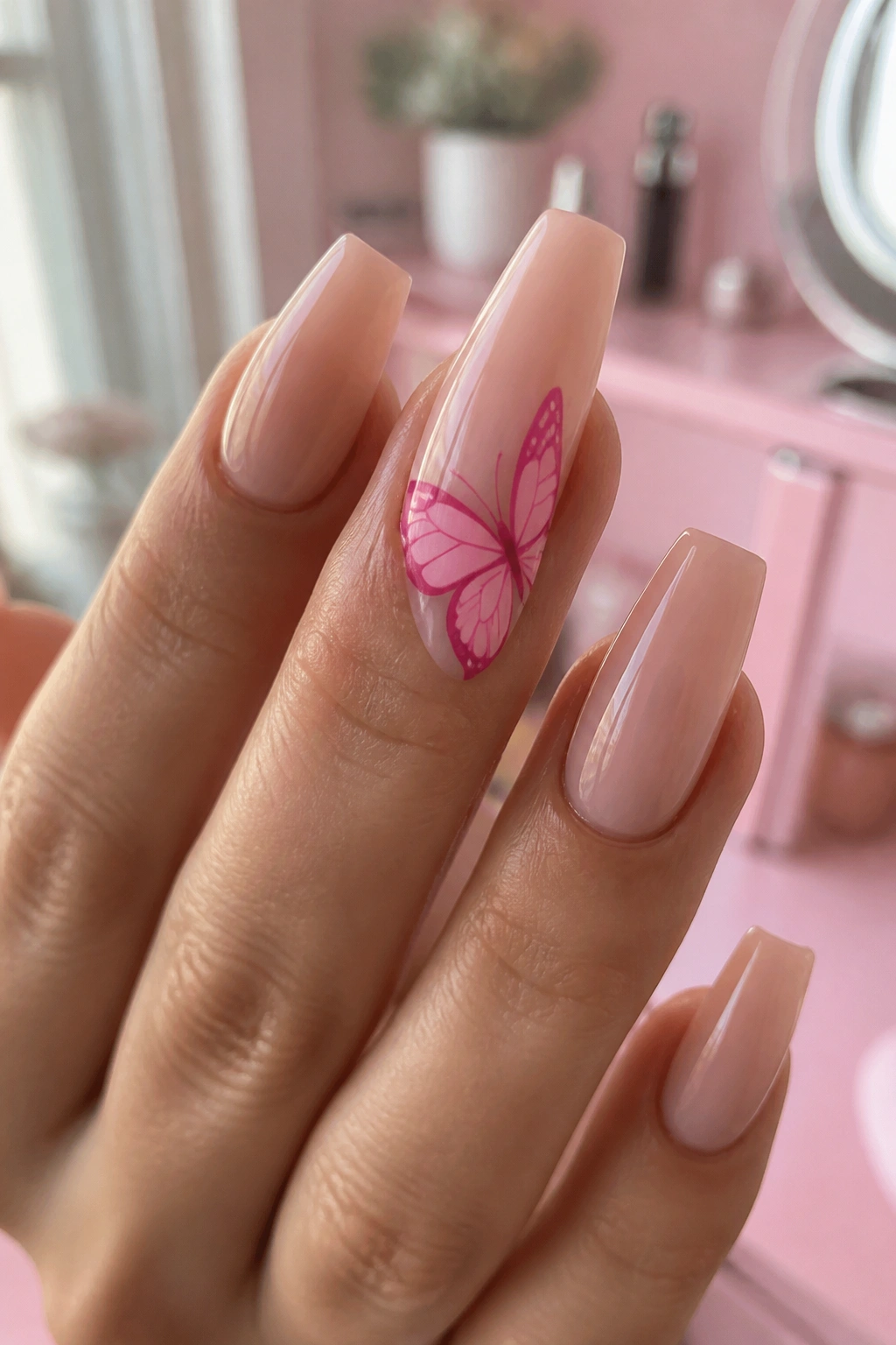 Close-up of butterfly nail art on nude-based hot pink coffin nails