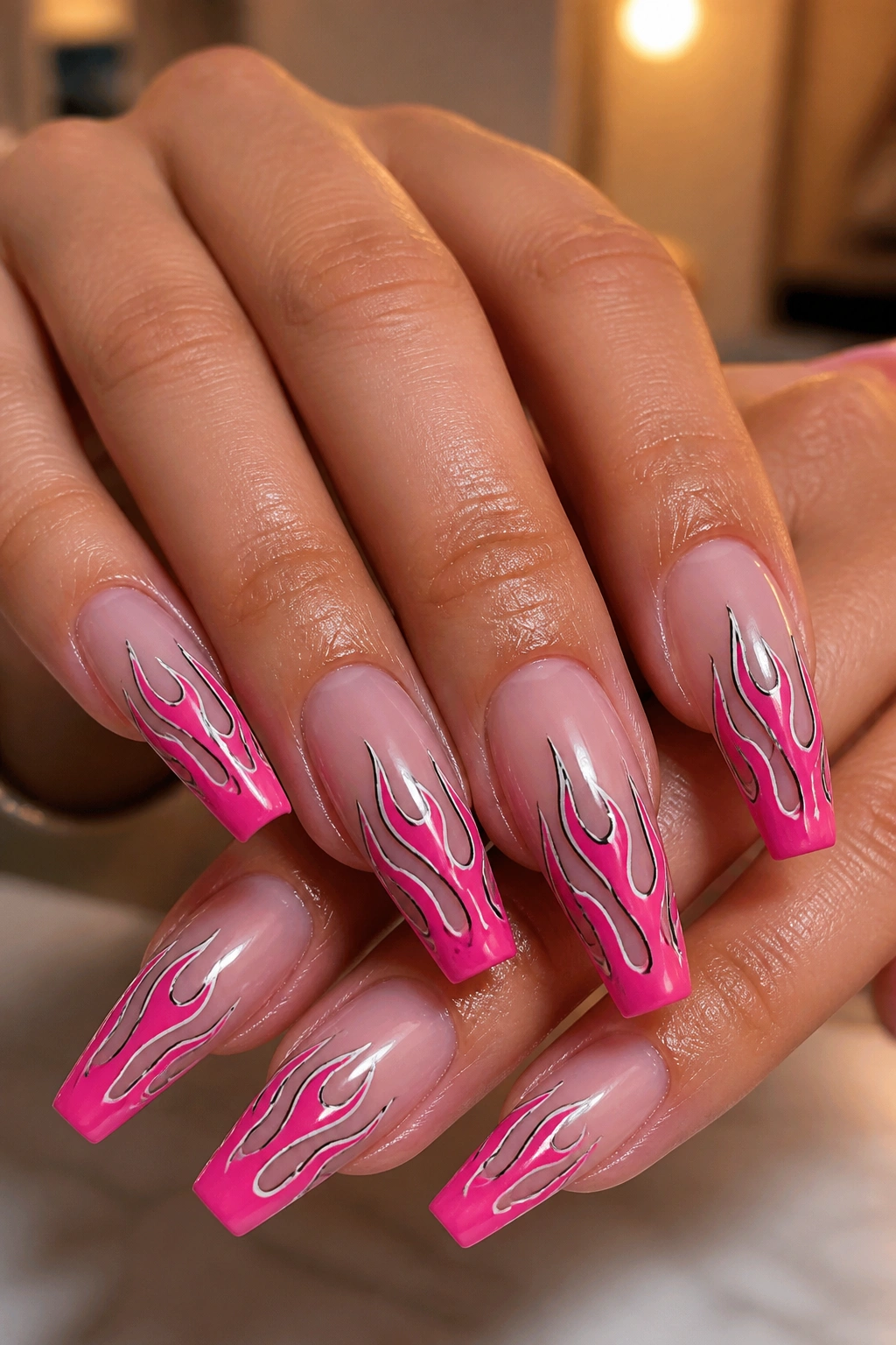 Close-up of nude-based hot pink flame nail art on coffin nails
