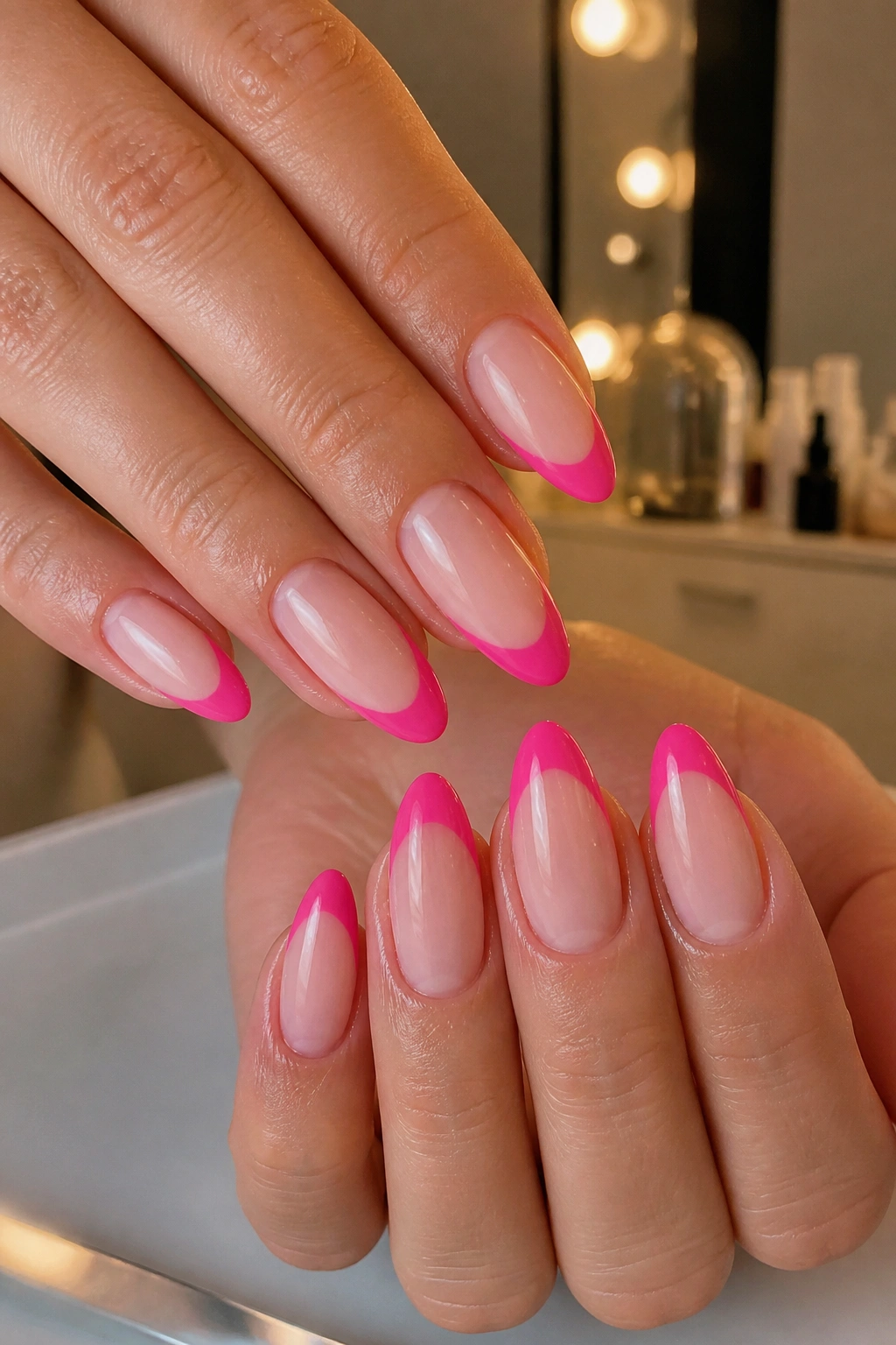 Close-up of almond nails with hot pink French tips on nude base