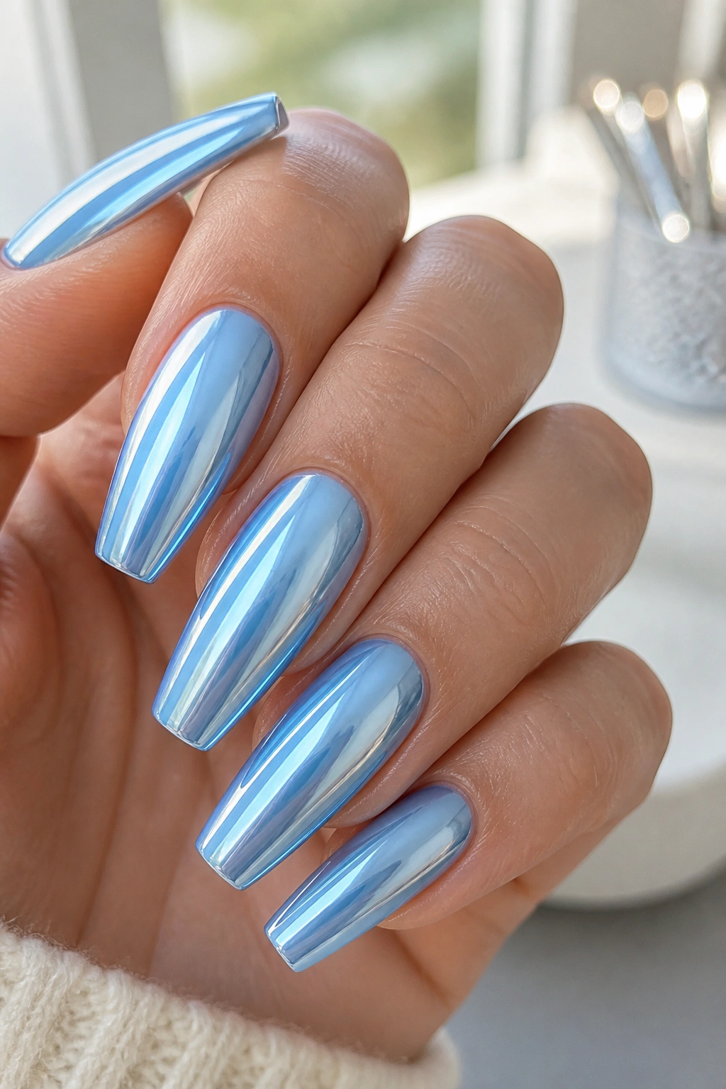Close-up of icy blue chrome coffin nails with milky base and glassy finish.