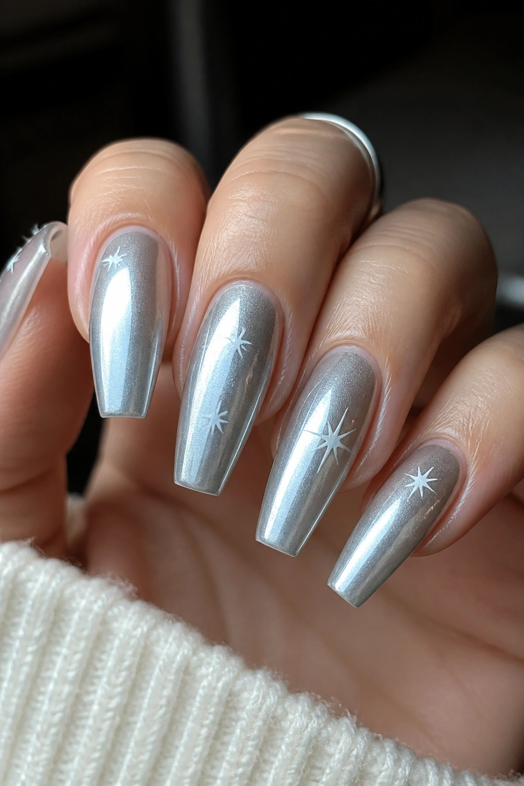Icy silver airbrush nails with white stars on a real hand