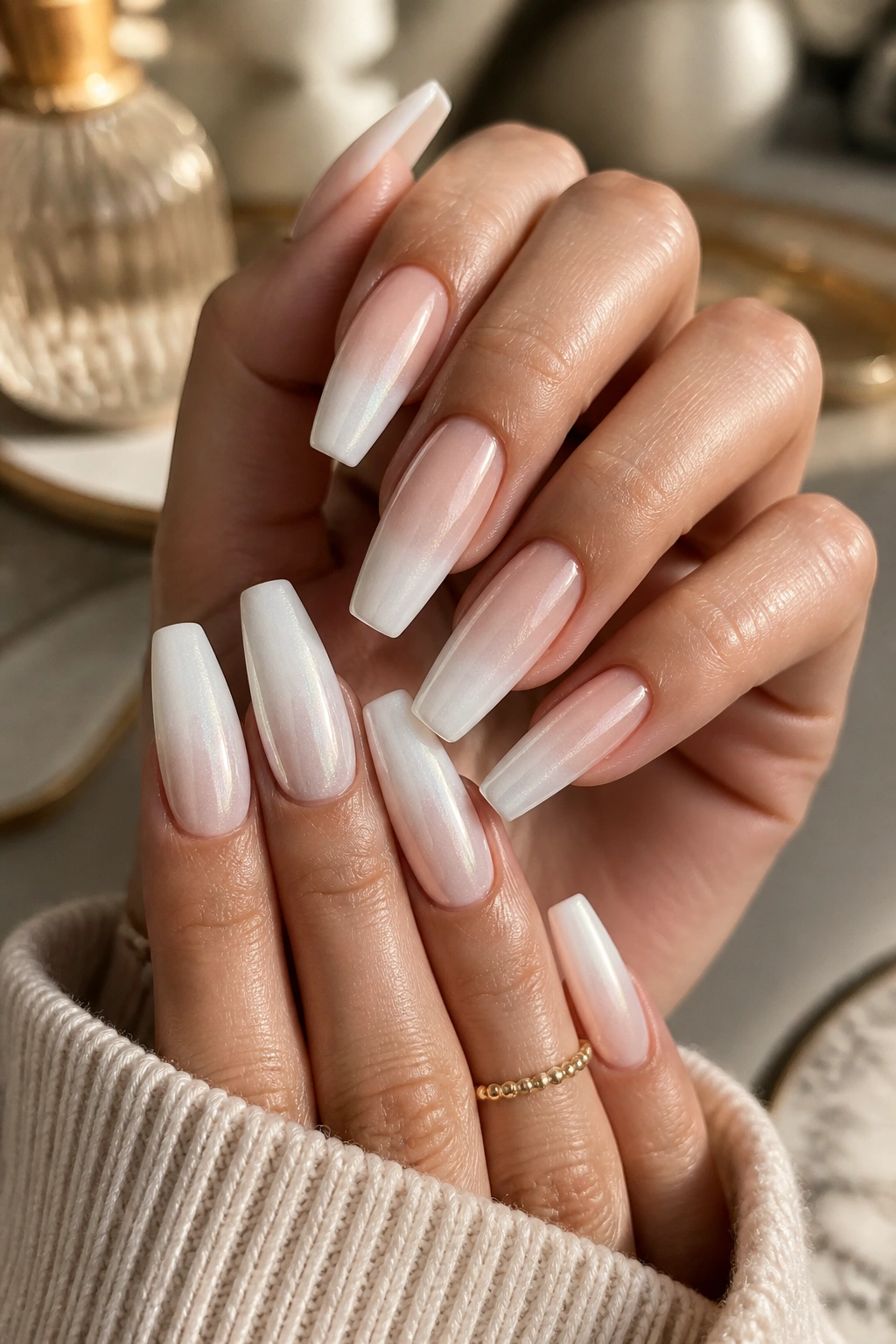 Close-up of hands with long coffin nails in ivory-white pearl powder fade under warm window light