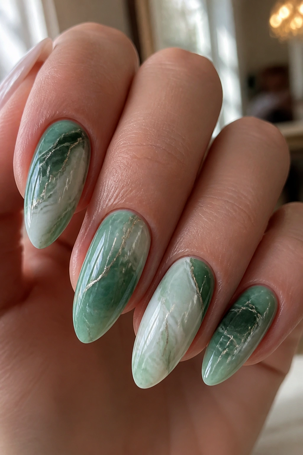 Close-up of jade and mint marble almond nails on a real hand