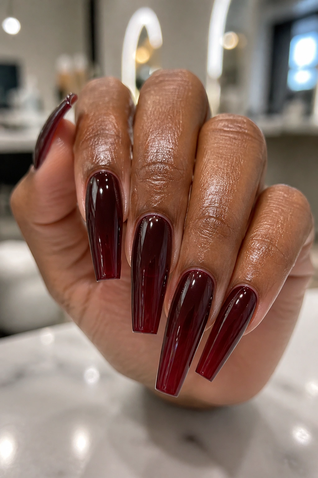 Close-up of jelly burgundy coffin nails showing translucent depth on a real hand