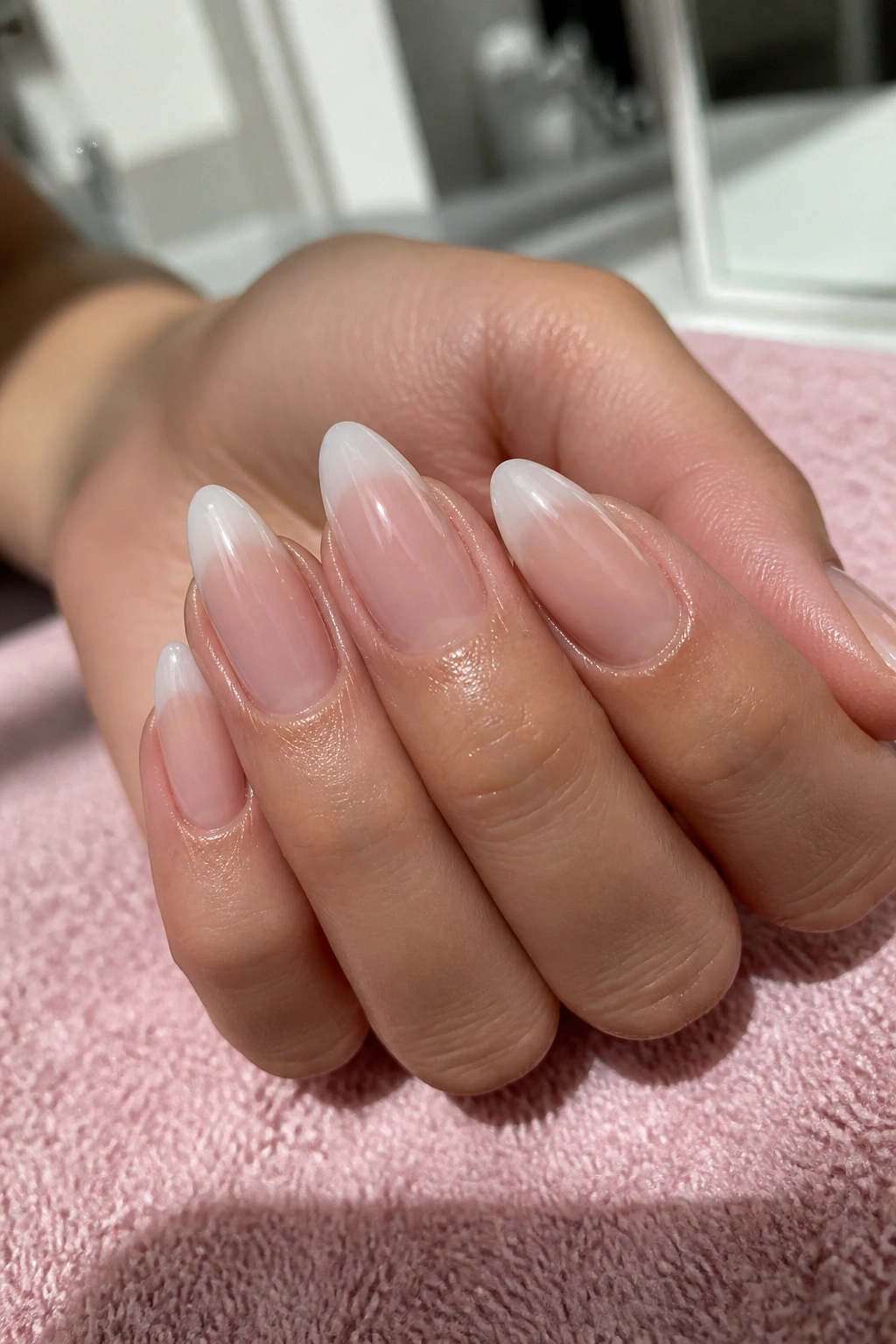 Close-up of almond nails with jelly nude ombre, sheer and glossy.