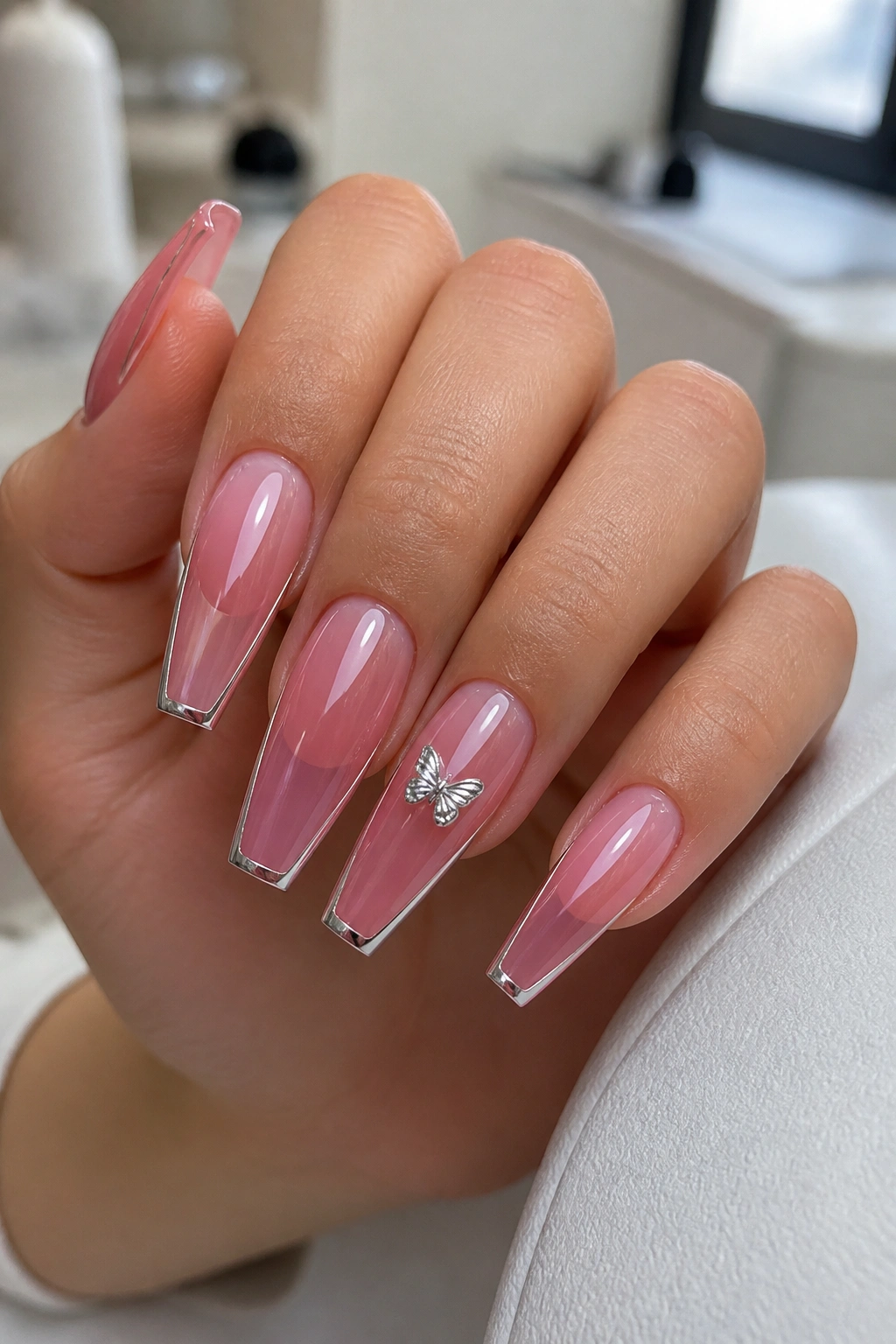 Close-up of jelly pink butterfly coffin nails with chrome edges on a real hand