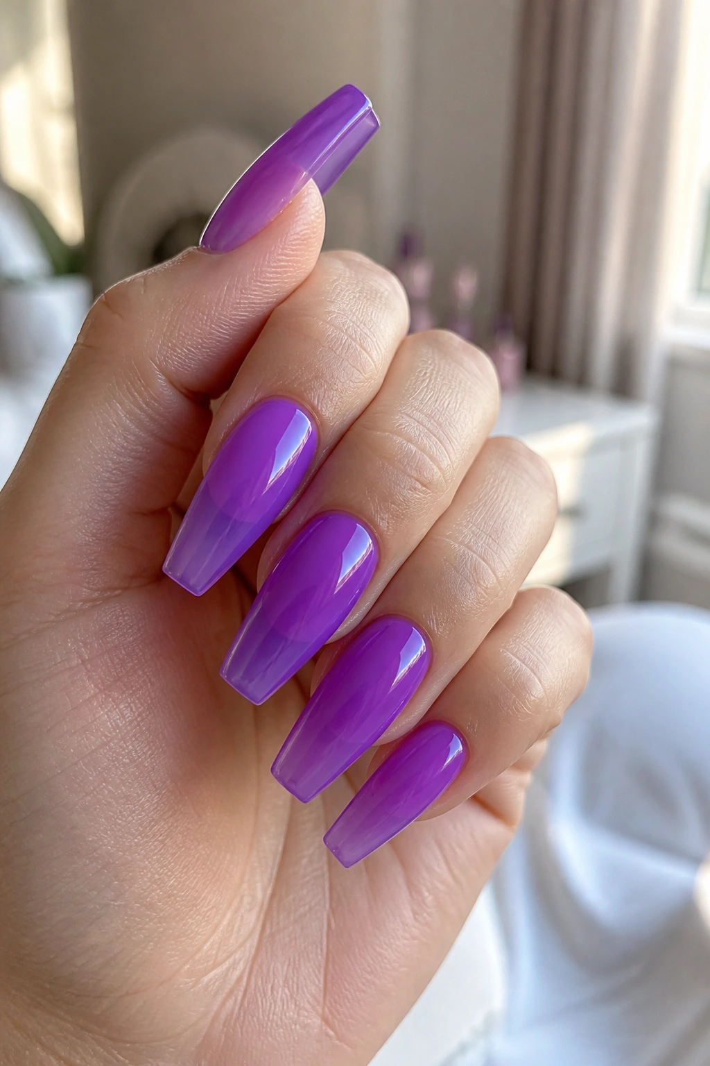 Close-up of jelly purple coffin nails on a real hand in sunlit vanity
