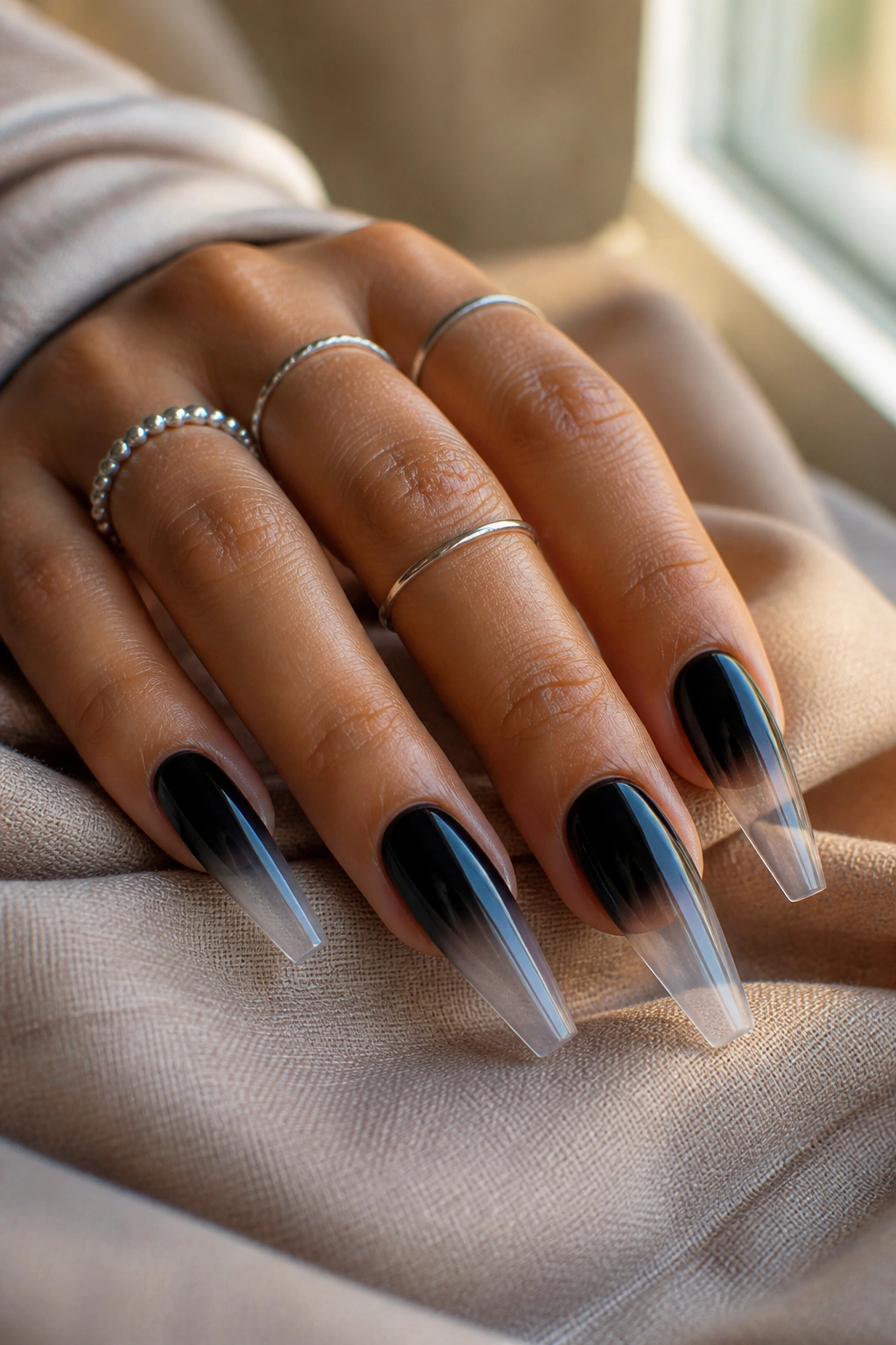 Close-up of long coffin nails with jet black to clear acrylic fade on a real hand.