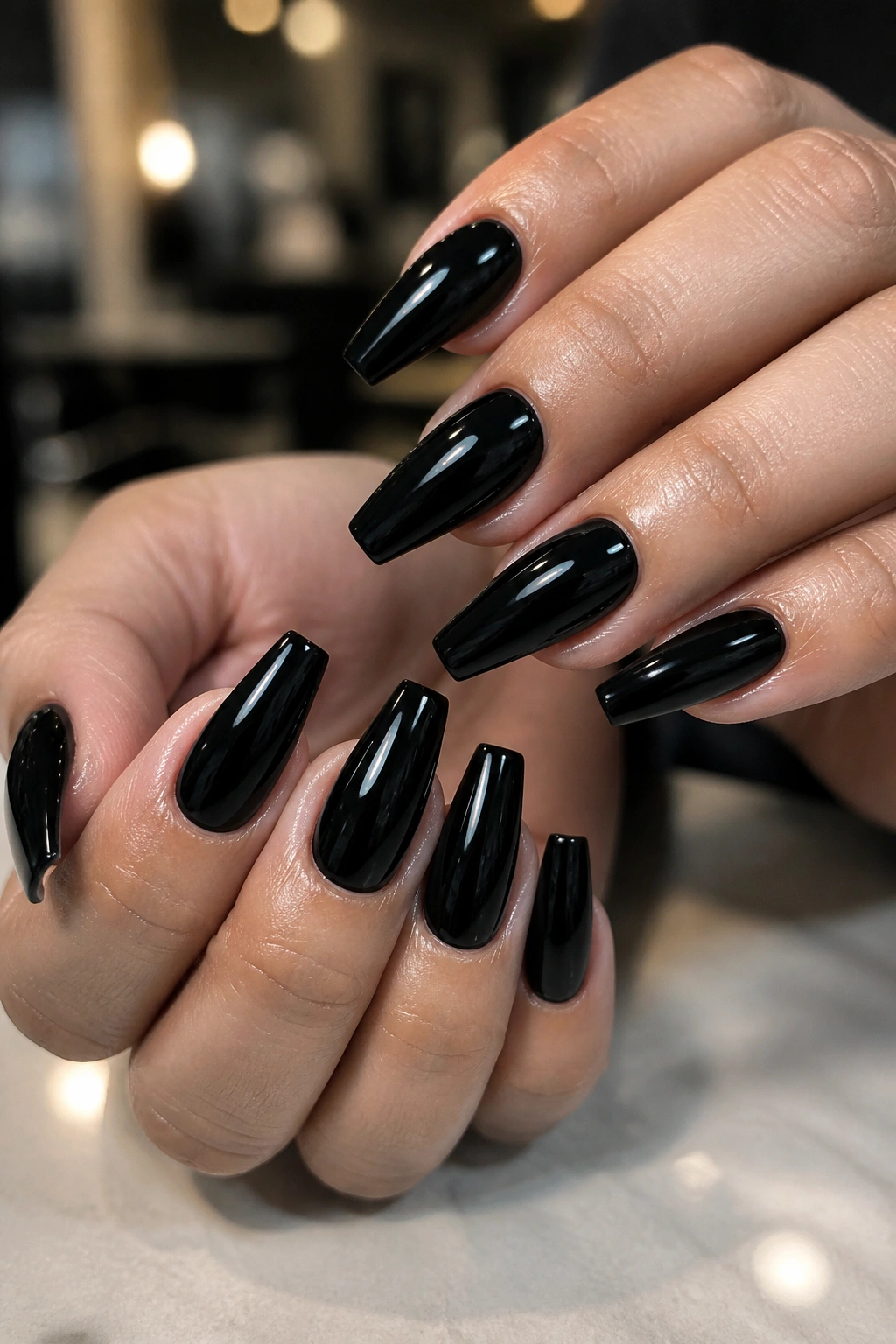 Close-up of real hands with jet black coffin nails finished in high gloss.