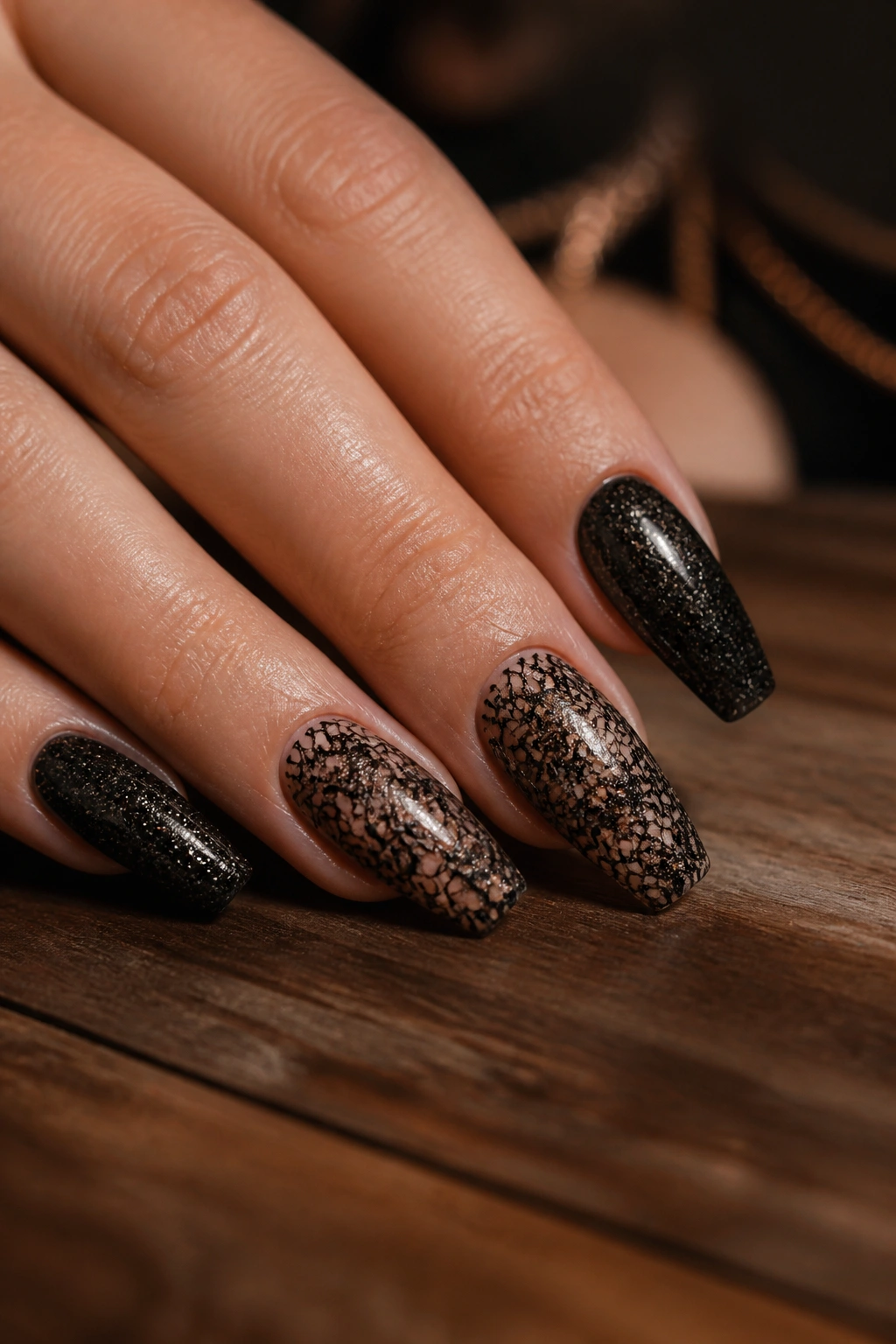 Nails with lace-pattern black glitter accents on a real hand