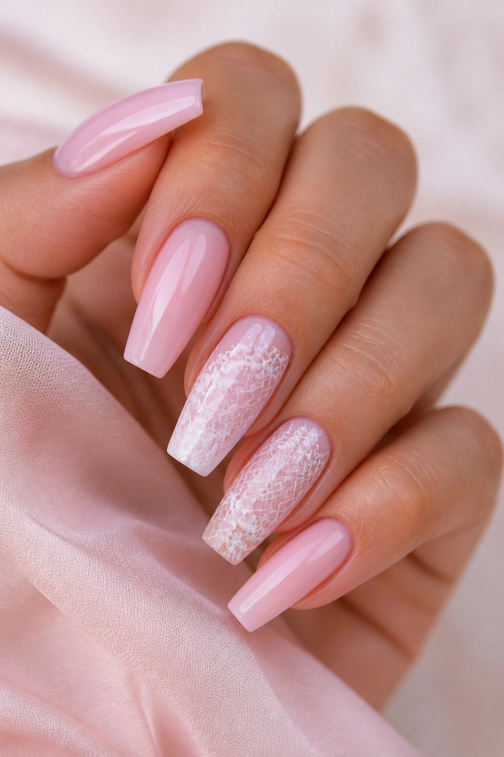 Nails with soft pink base and white lace veil art on select nails