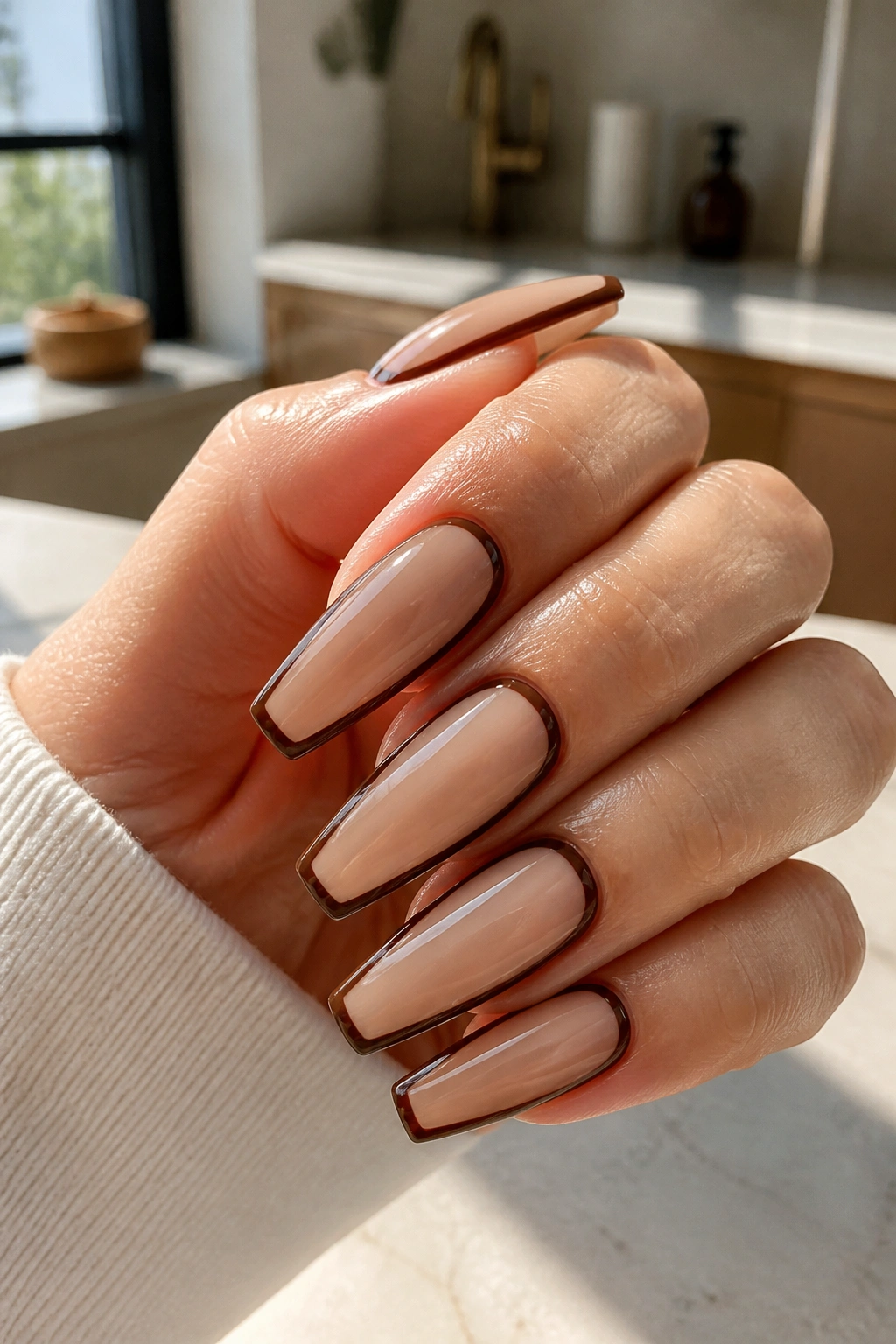 Close-up of Latte Nude Coffin Nails With Dark Brown Outline on real hand