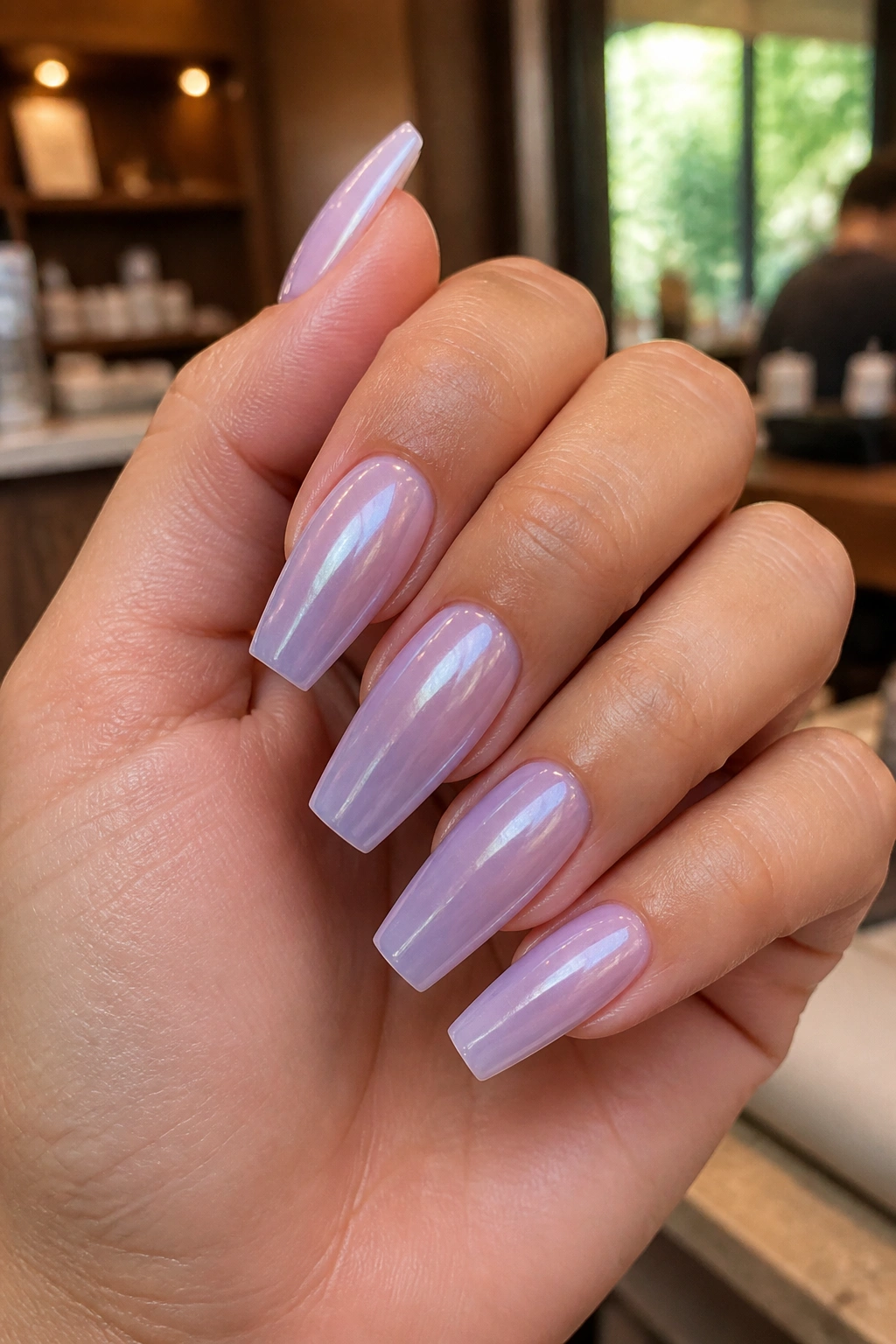 Close-up of milky lavender chrome coffin nails on a real hand in a salon