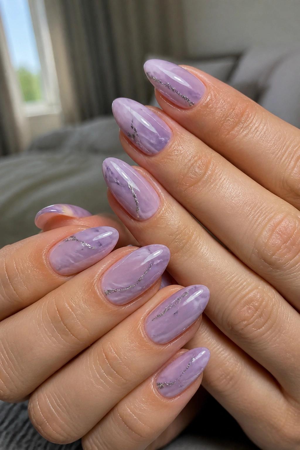 Close-up of almond nails in lavender marble with silver flicks on real hands