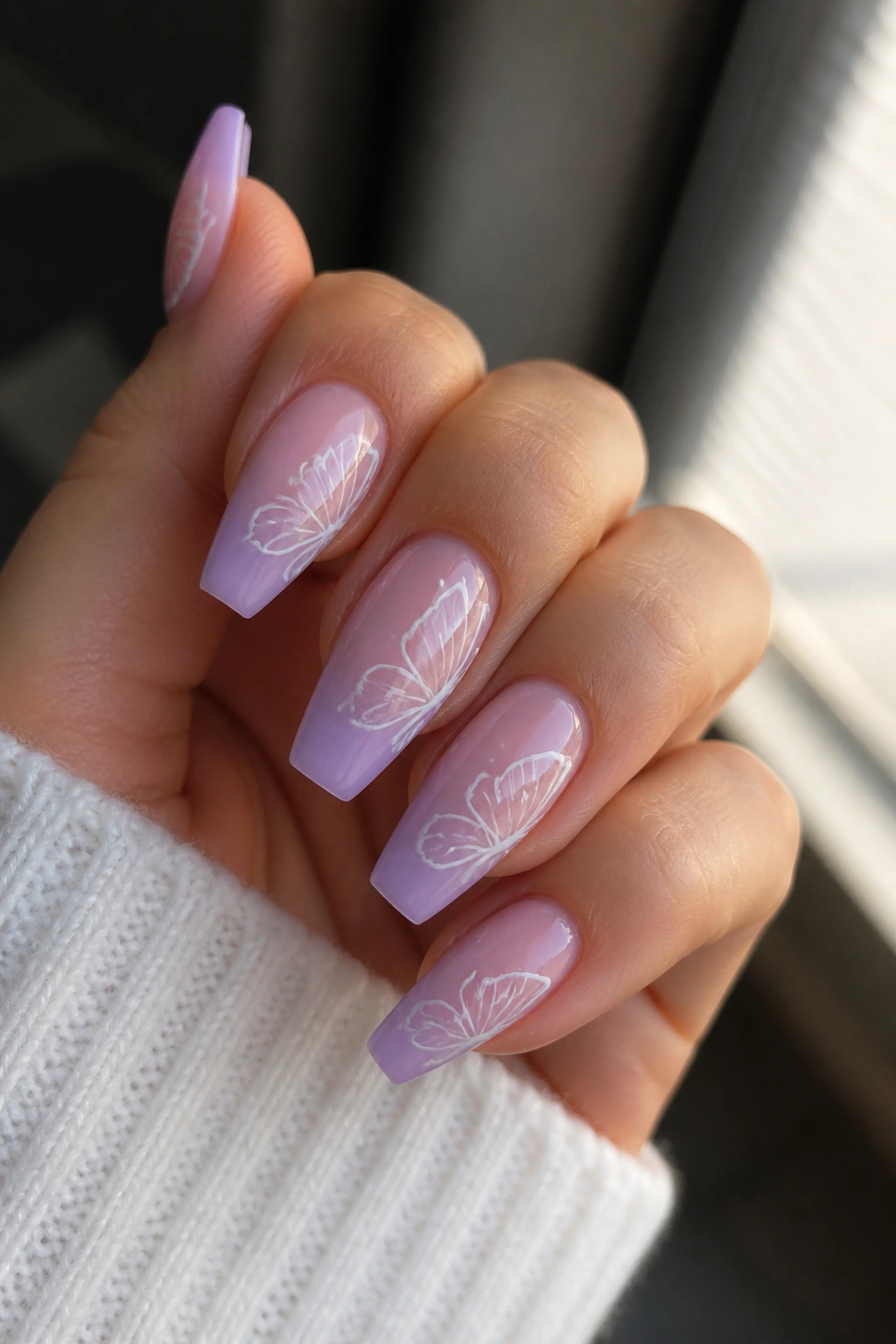 Lavender ombre coffin nails with white butterfly linework on real hand