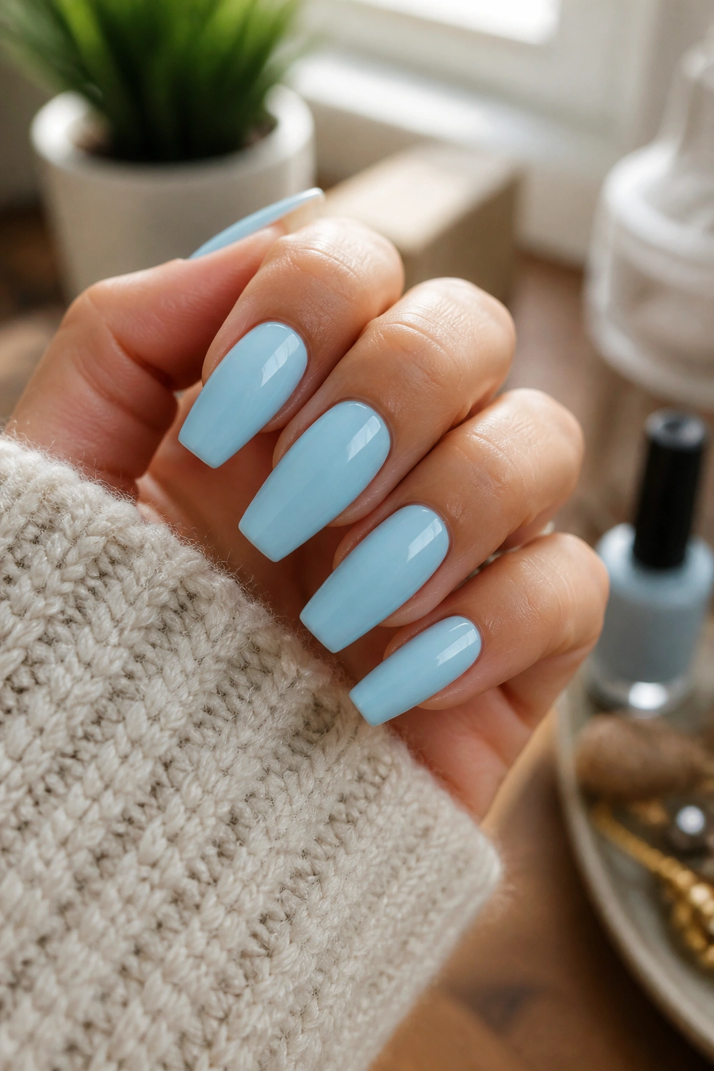Close-up of pale blue coffin nails on a real hand in a cozy manicure setting