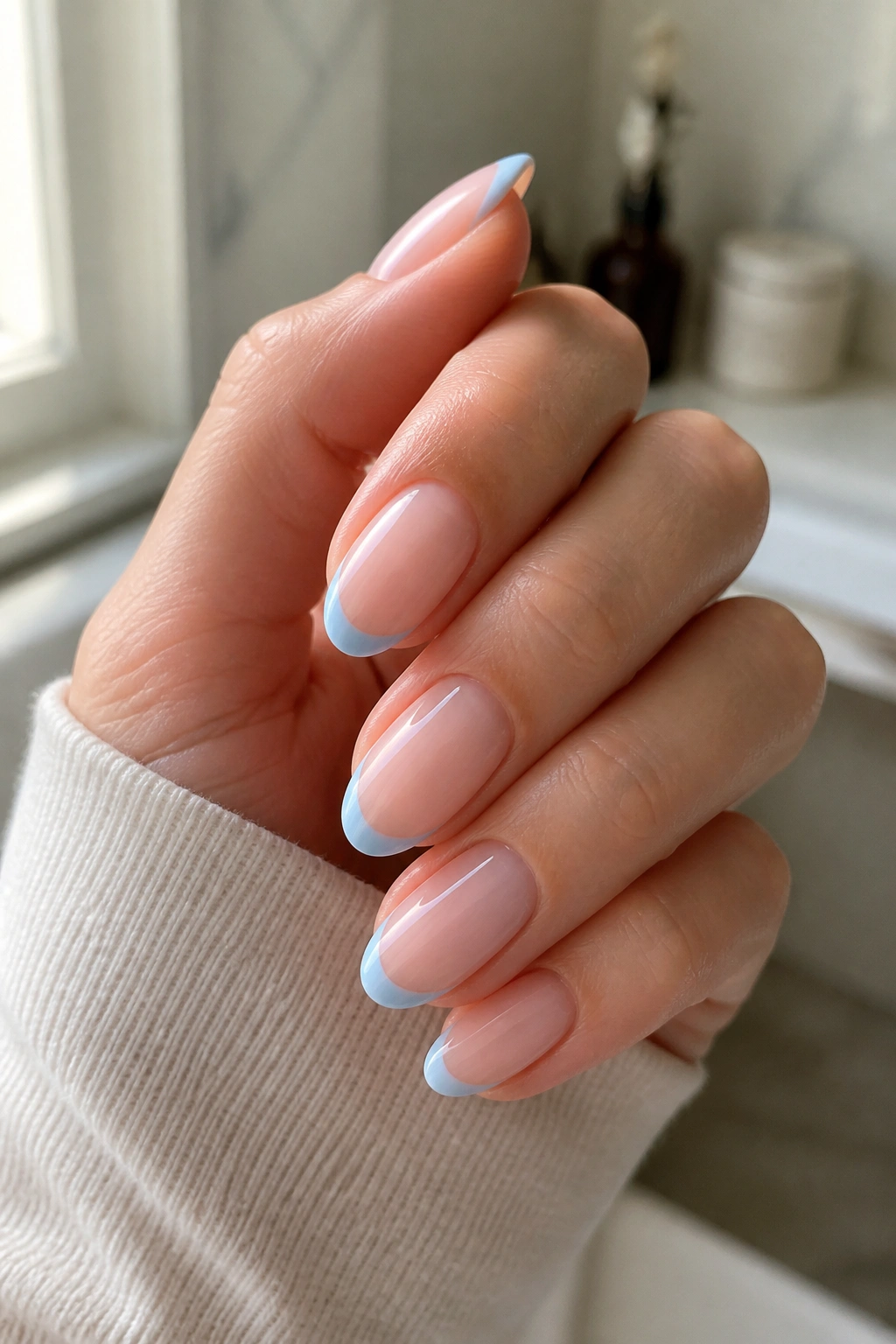 Close-up of almond nails with pale blue micro-French tips on a real hand
