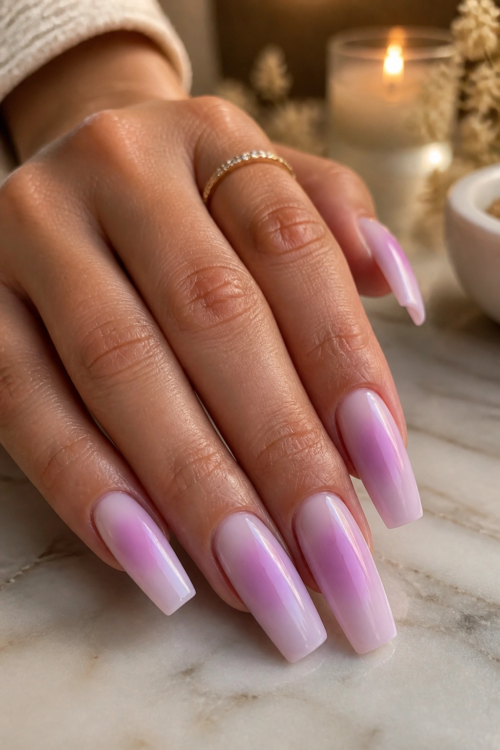 Close-up of a real hand with lilac aura coffin nails featuring a milky base and centered violet halo in a spa-like vanity.