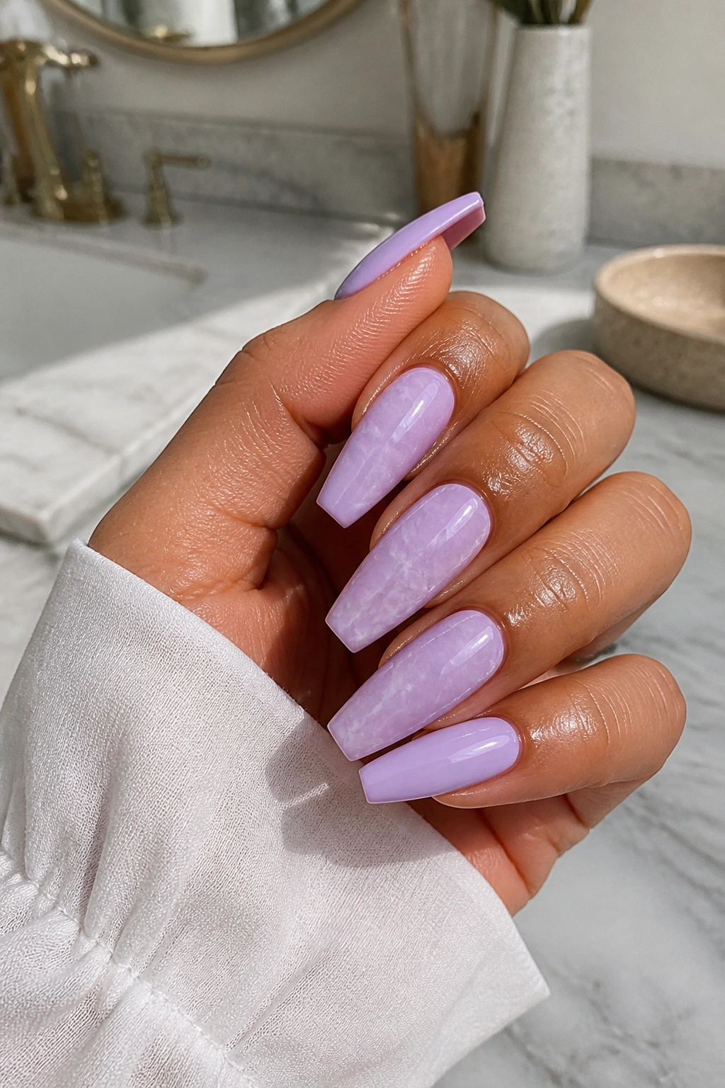 Lilac marble coffin nails with white veins on hand, close-up.