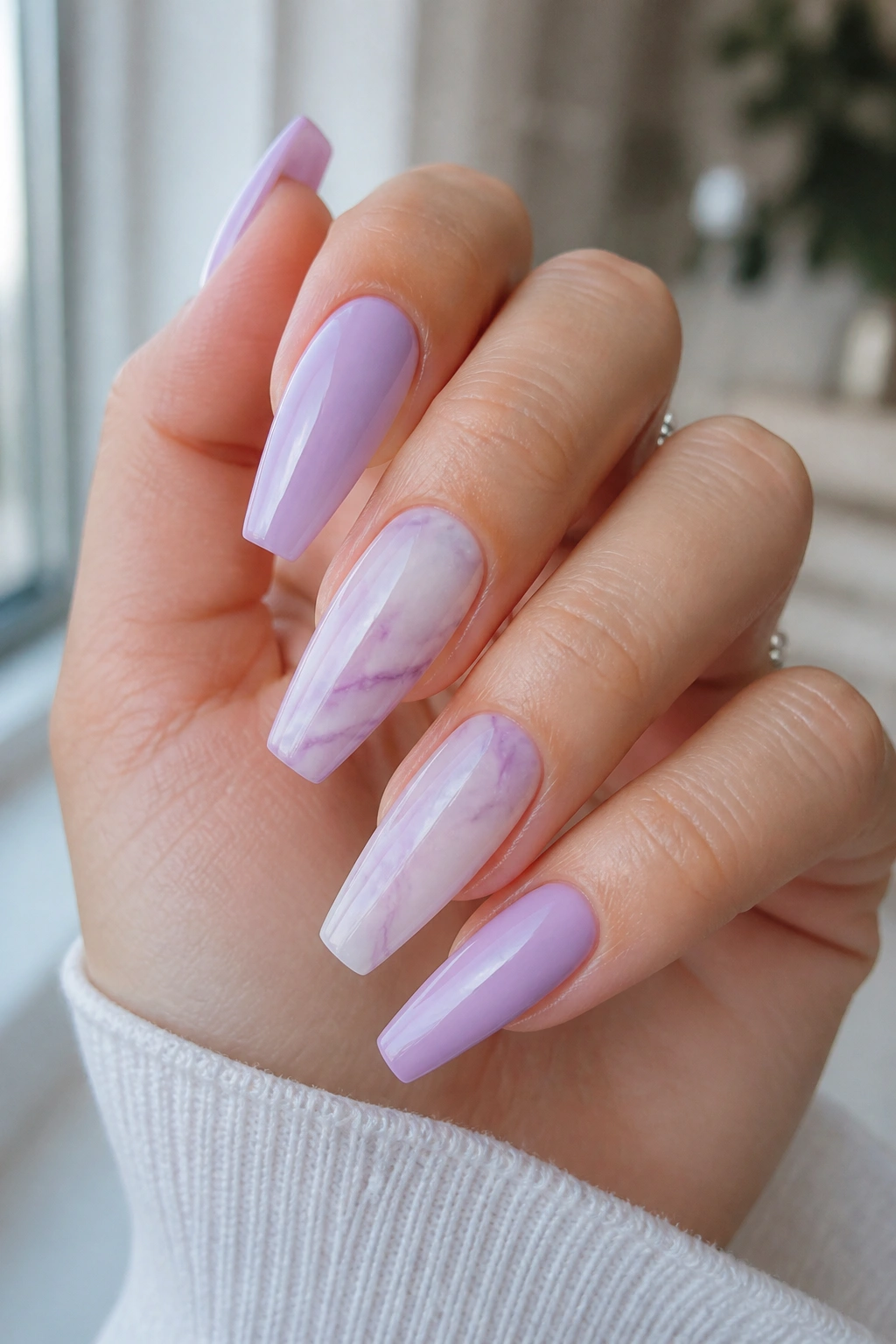 Nails with lilac and white marble on a milky base, close-up on a real hand