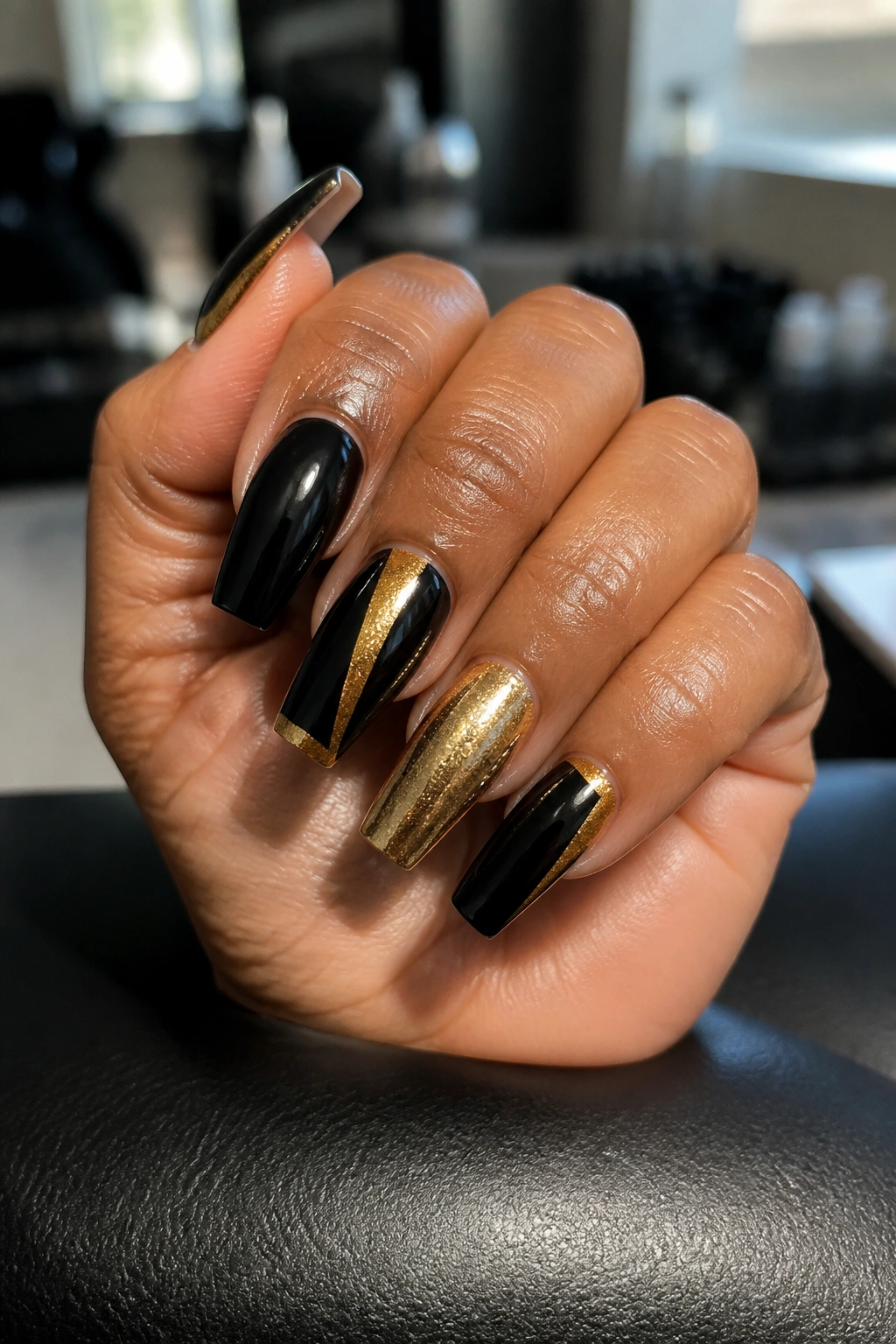 Close-up of long coffin nails with black and gold glossy finish