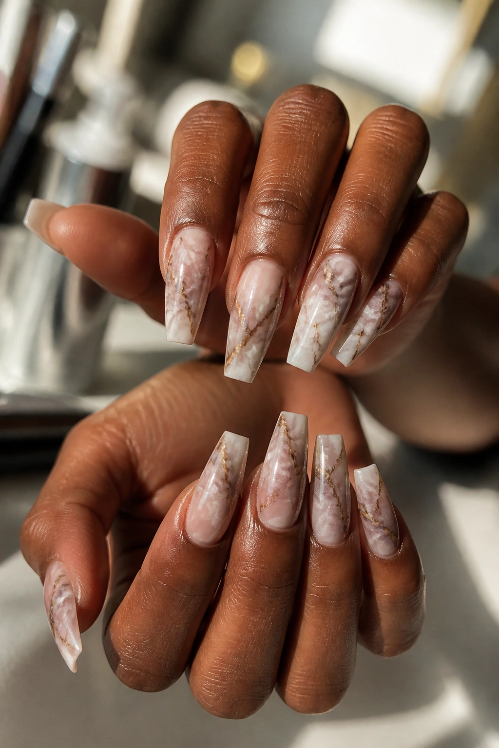 Close-up of hands with marble coffin nails in a sunlit salon