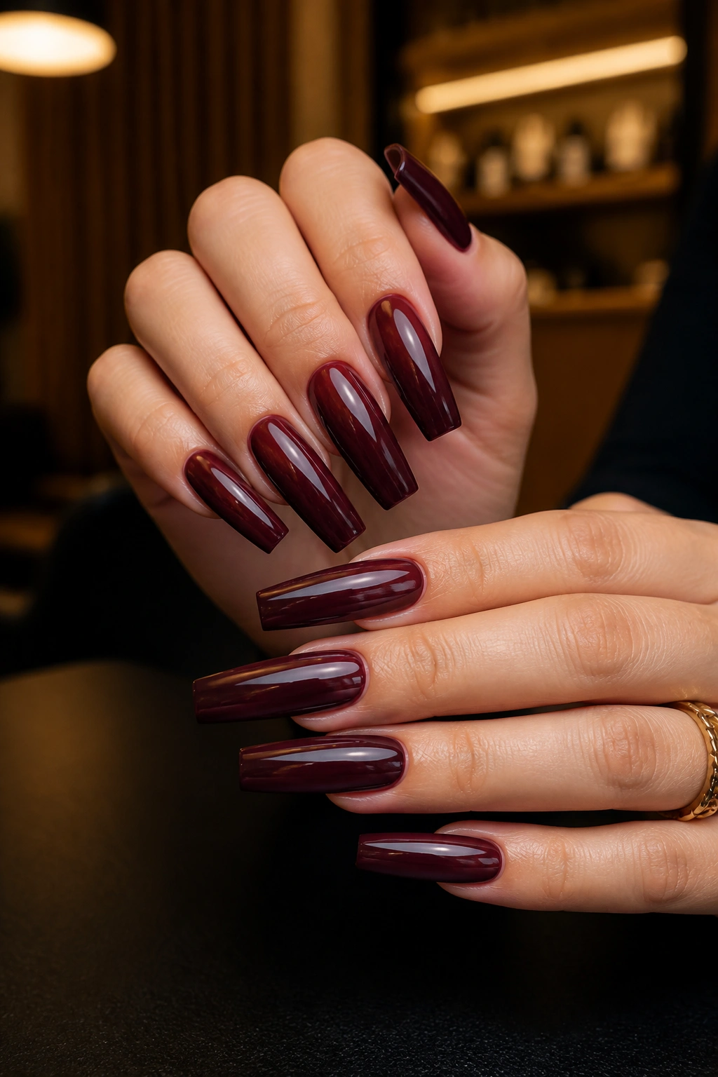 Close-up of maroon coffin nails on a real hand in a salon setting