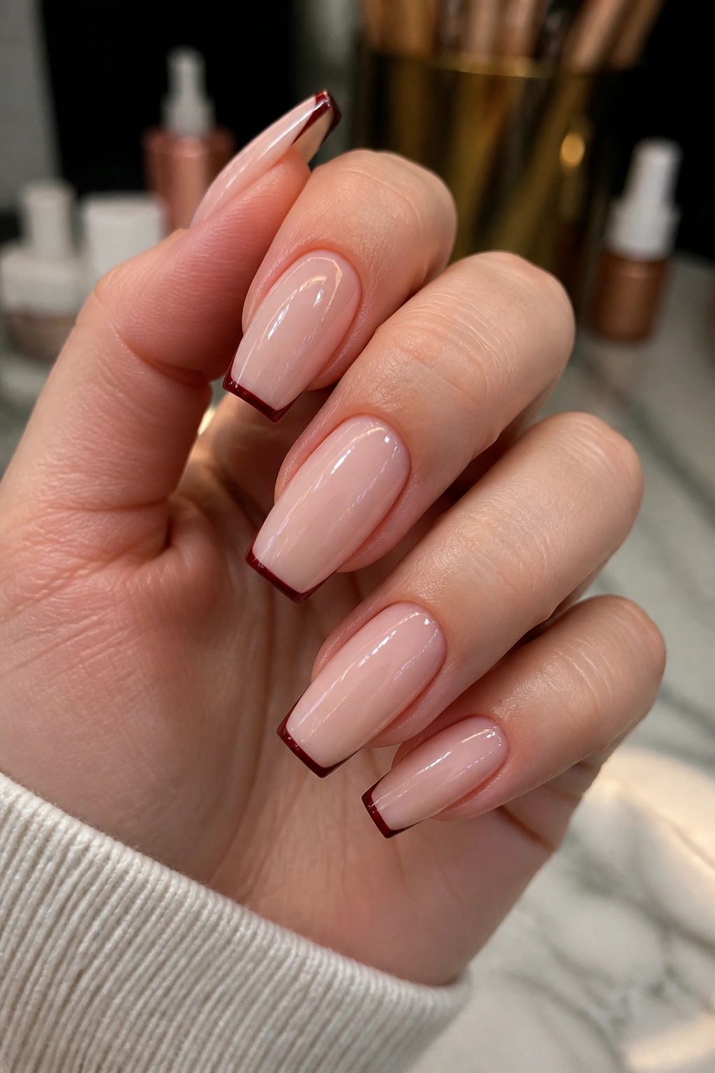 Close-up of nude-based maroon micro-French coffin nails.