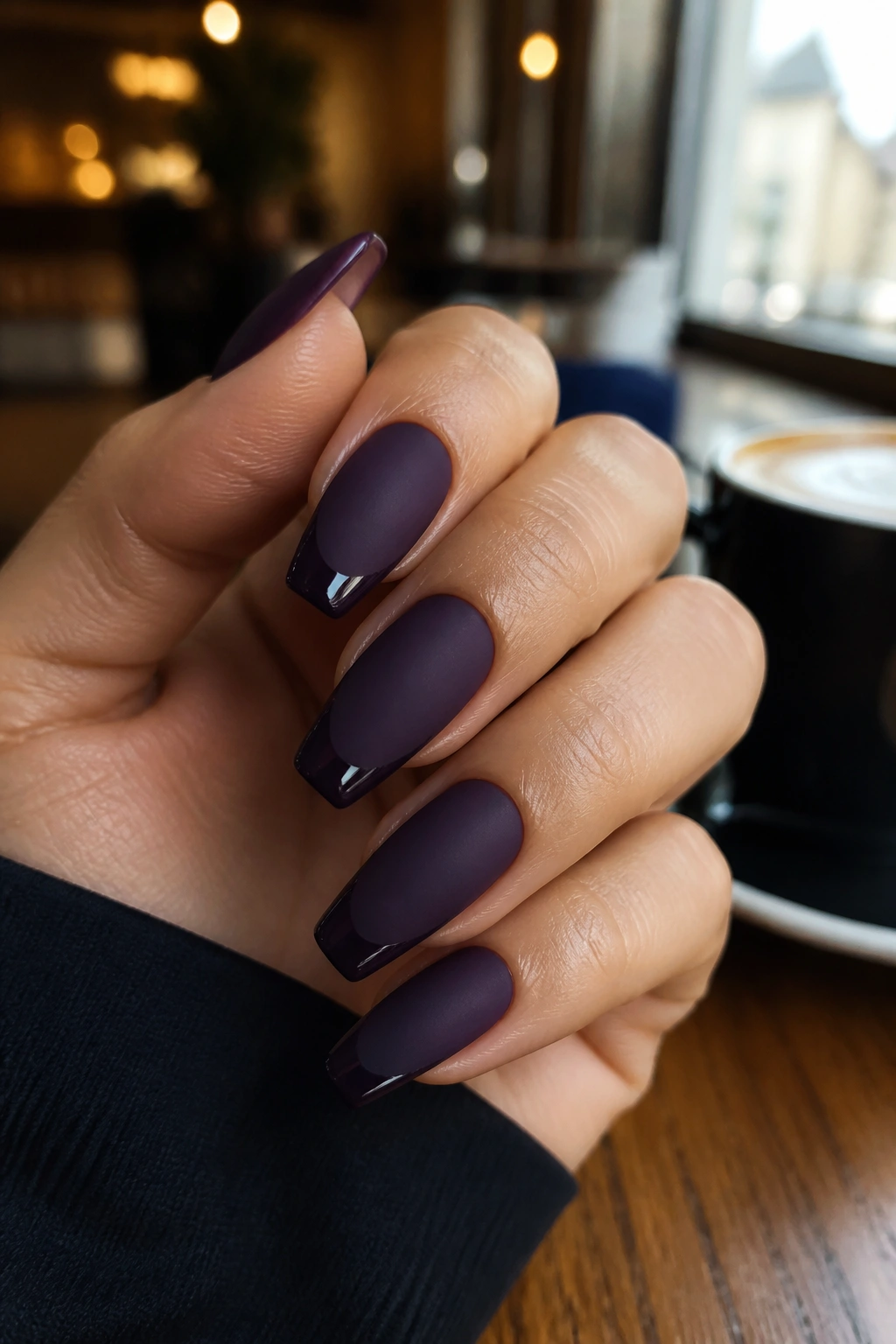 Close-up of matte aubergine coffin nails with glossy tips on a real hand