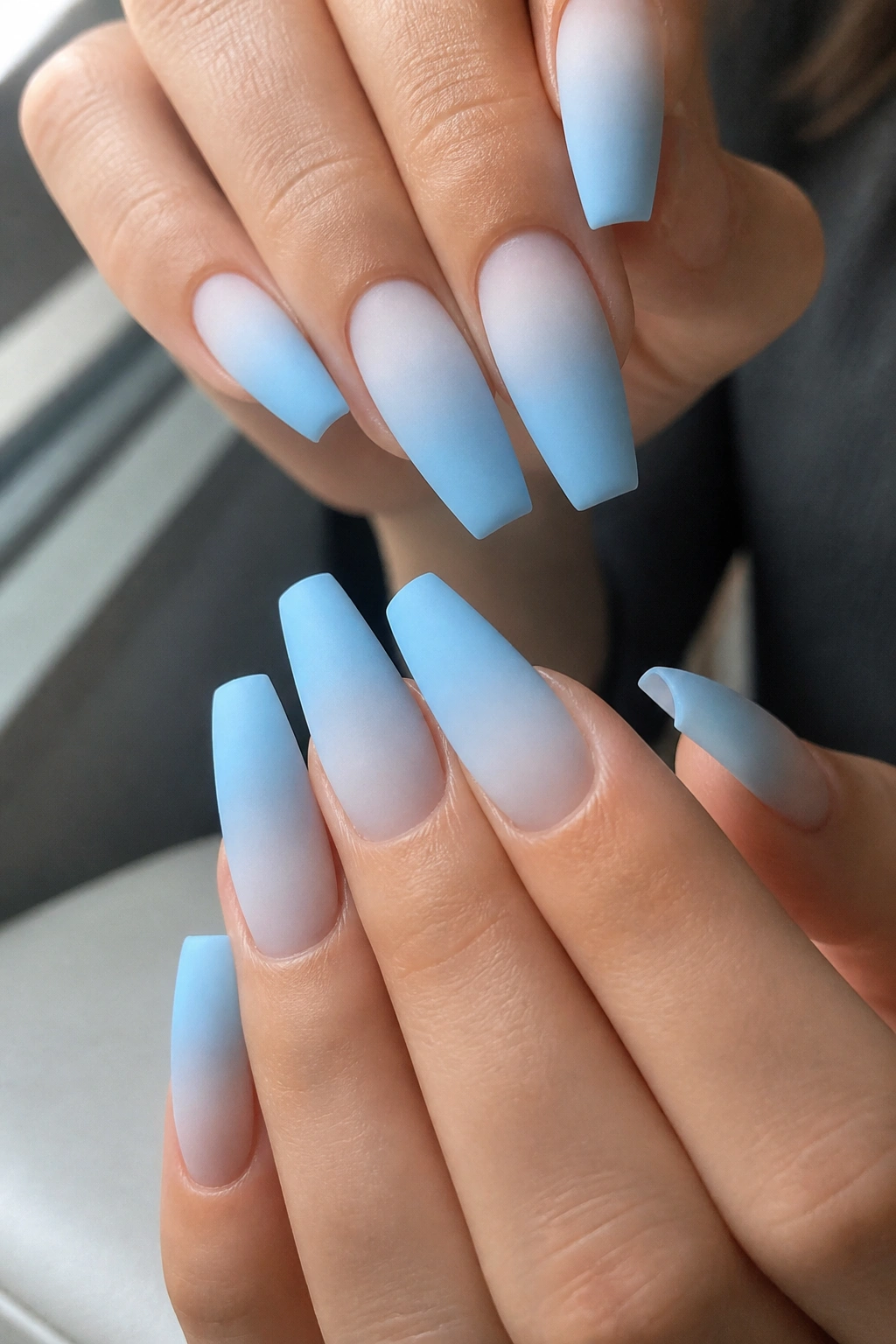 Close-up of matte powder blue ombre coffin nails on a real hand in a salon